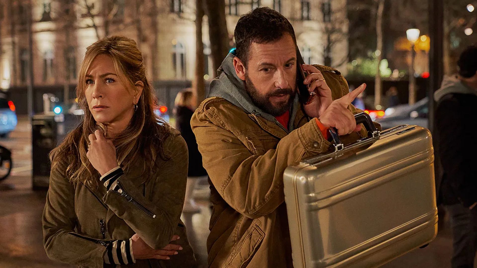 Jennifer Aniston i Adam Sandler na ulicy, ona wygląda na przestraszoną, on rozmawia przez telefon i trzyma teczkę
