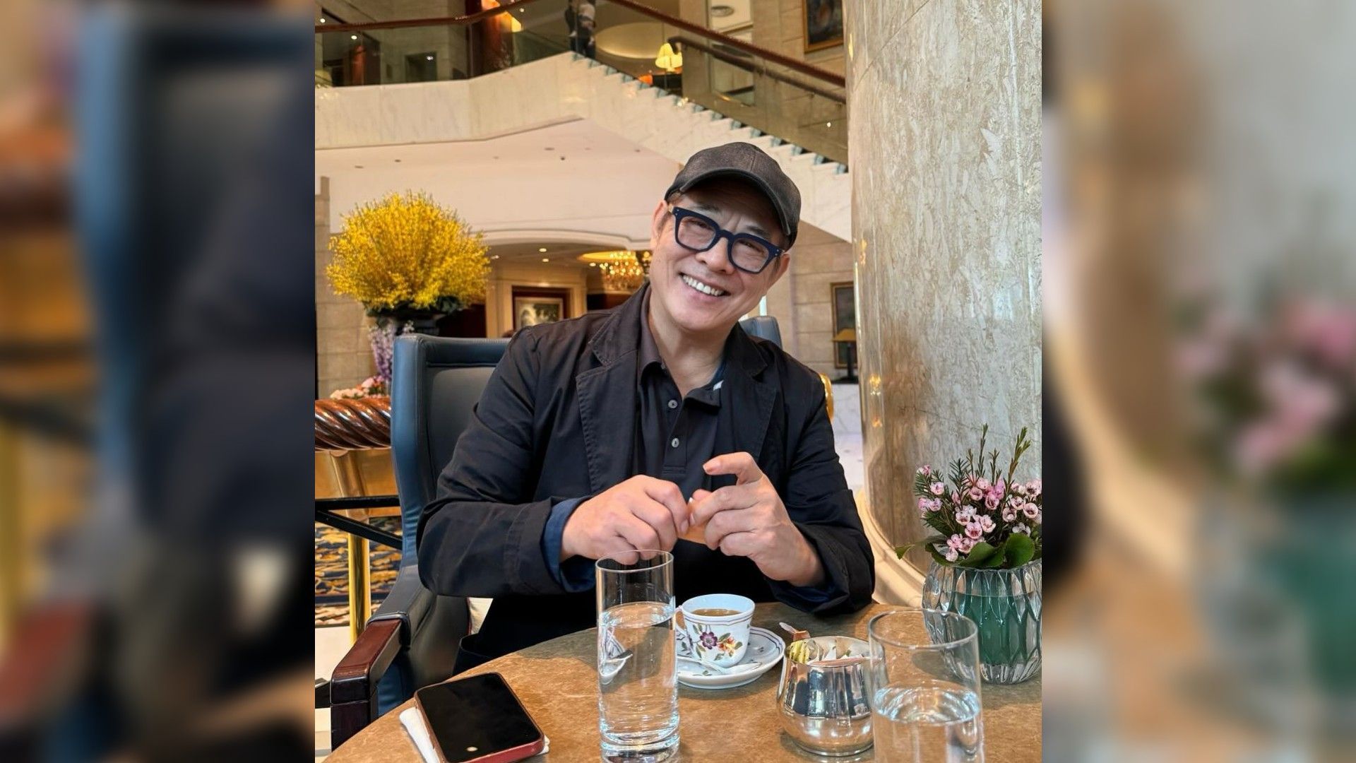 Jet Li w czapce i okularach przeciwsłonecznych jedzący w restauracji