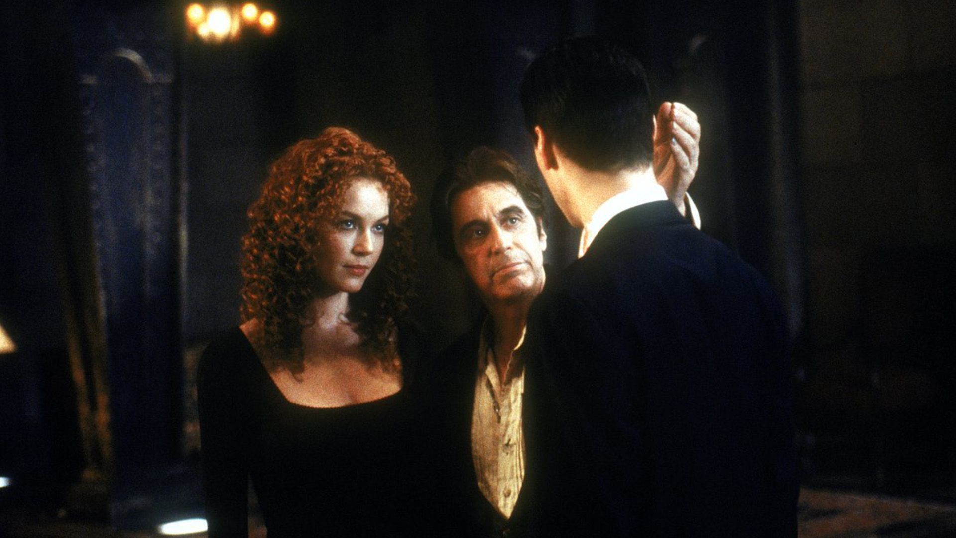Connie Nielsen z długimi kręconymi włosami stoi obok Ala Pacino rozmawiającego z Keanu Reevesem