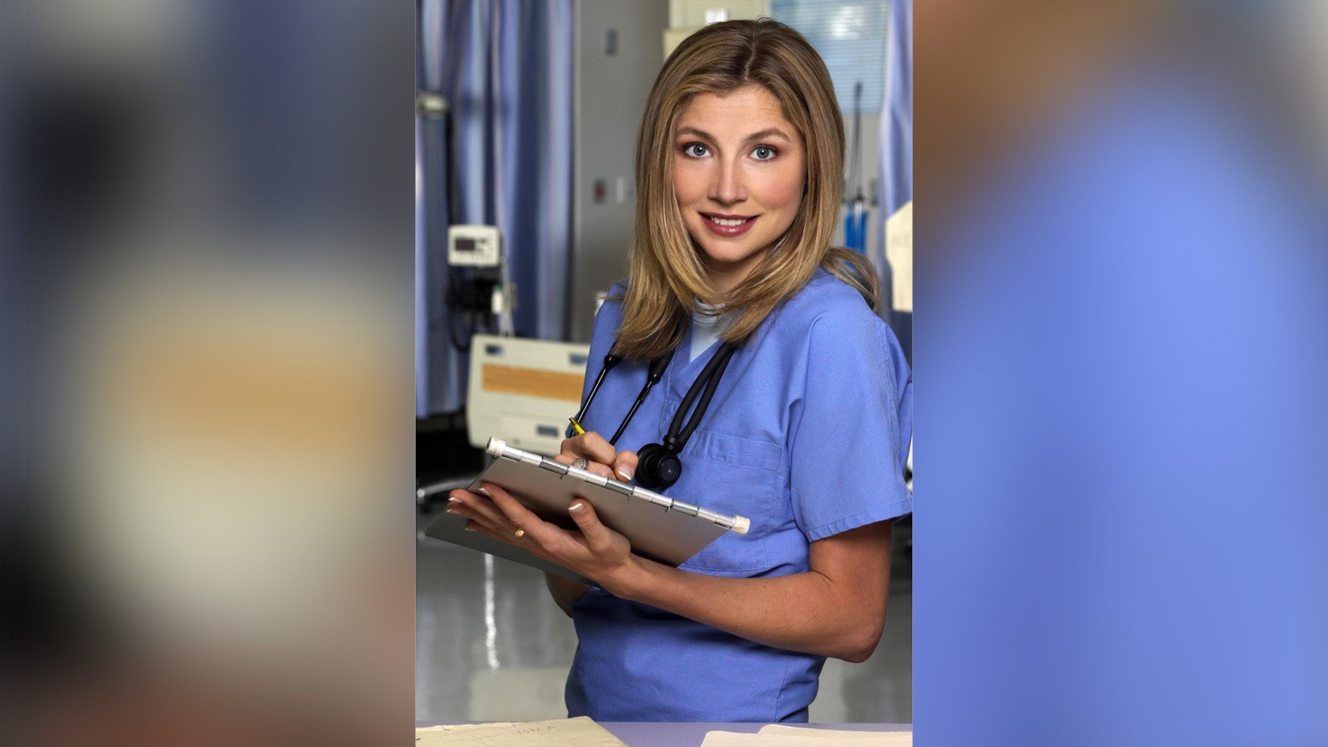 Sarah Chalke w lekarskim fartuchu z podkładką do pisania w rękach