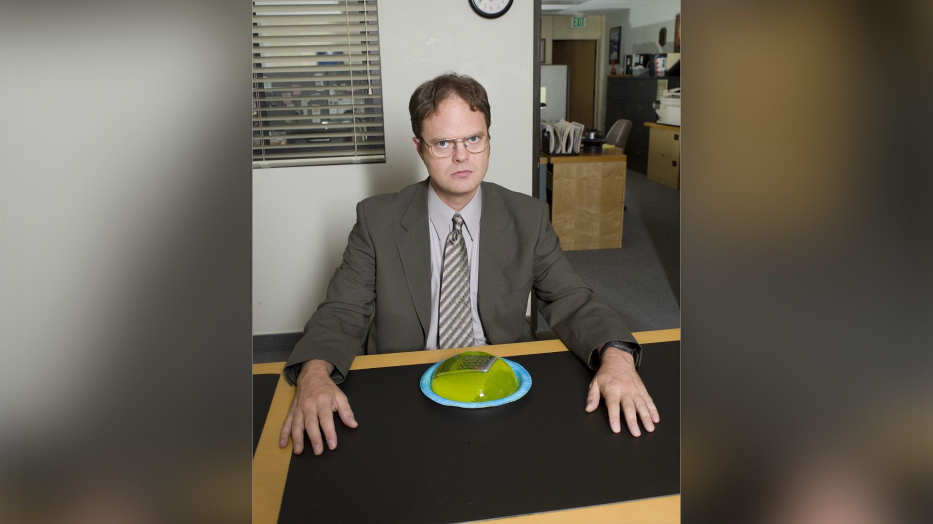 Rainn Wilson siedzi przy stole z talerzem, na którym leży kalkulator zalany zielonym galaretką