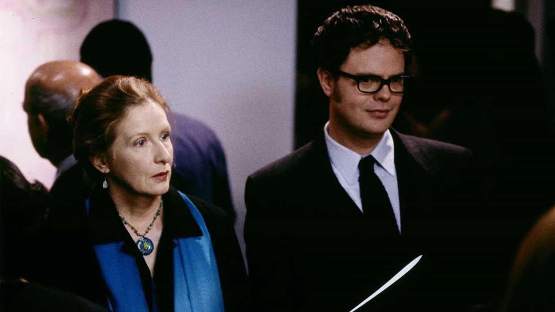 Rainn Wilson w okularach i marynarce, stojący obok Frances Conroy w niebieskim szaliku