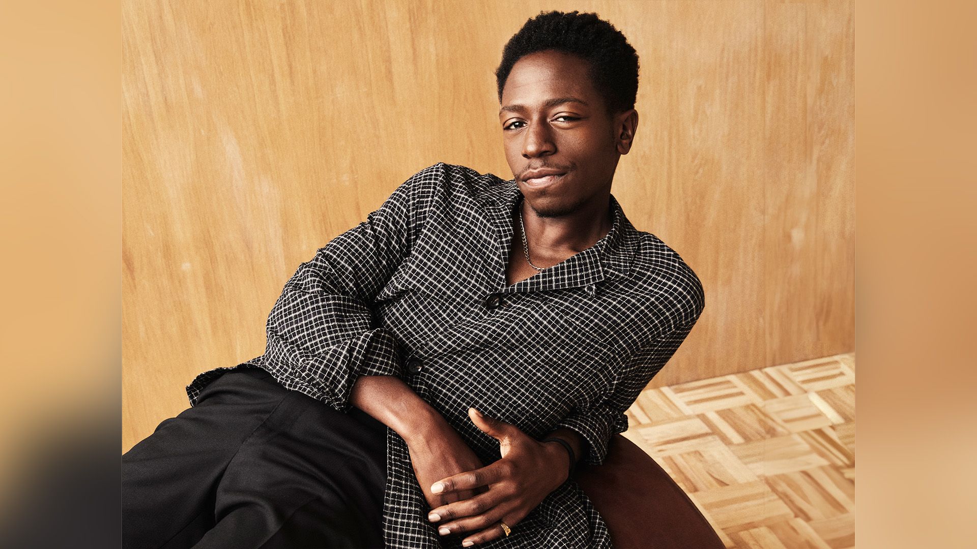 Aktor David Jonsson w czarno-białej koszuli w kratę, leżący oparty na jednym ramieniu