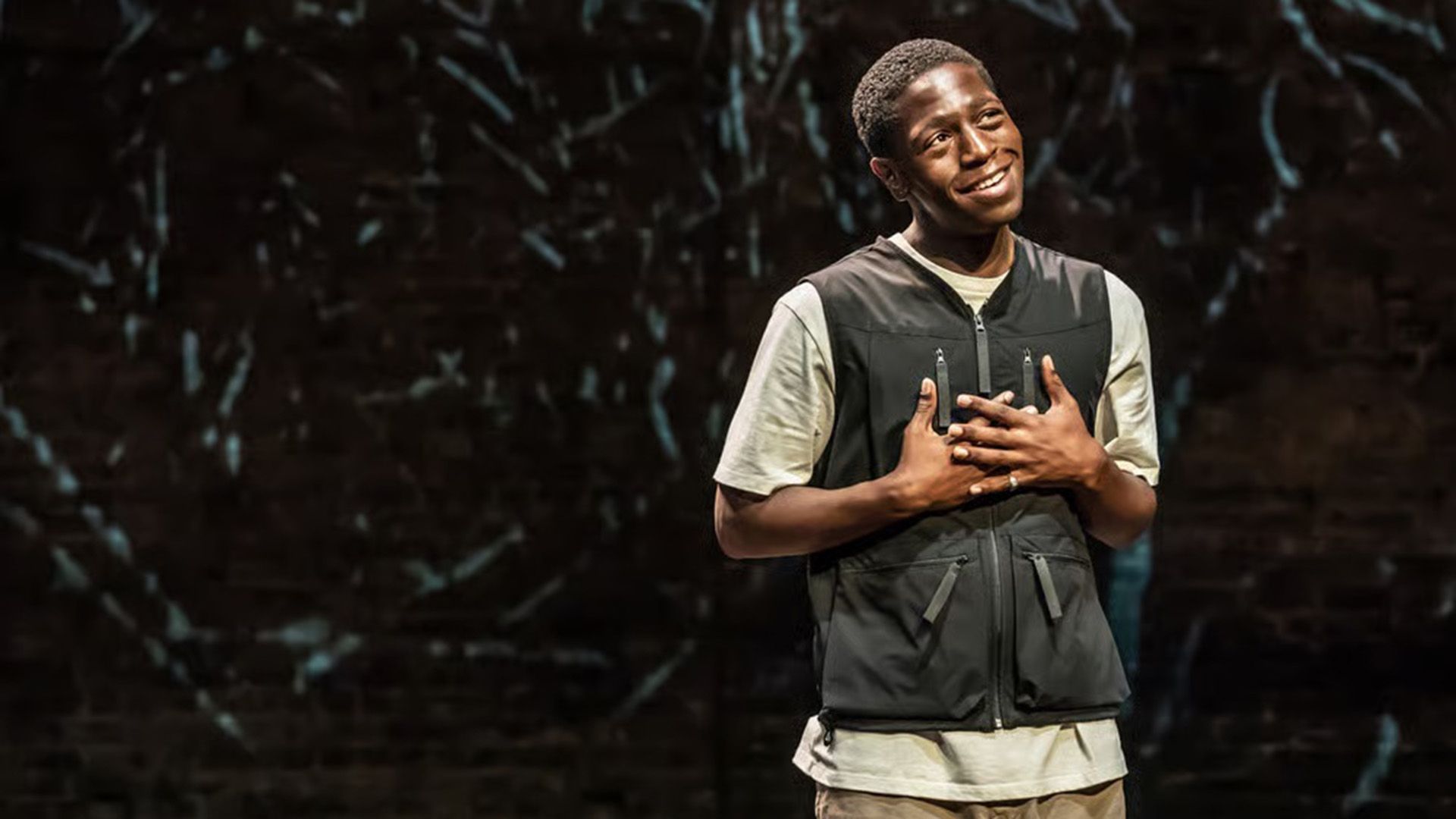 David Jonsson w białym t-shircie i czarnej kamizelce patrzy marzycielsko w górę z dłońmi złożonymi na piersi