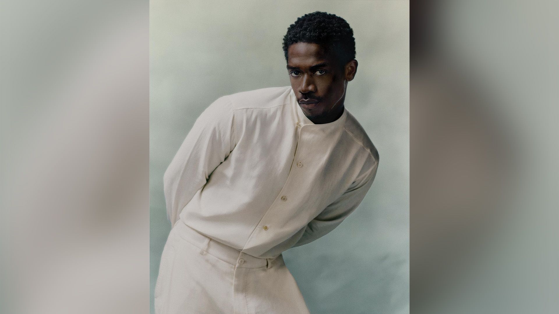 Aktor Damson Idris w białej koszuli i białych spodniach