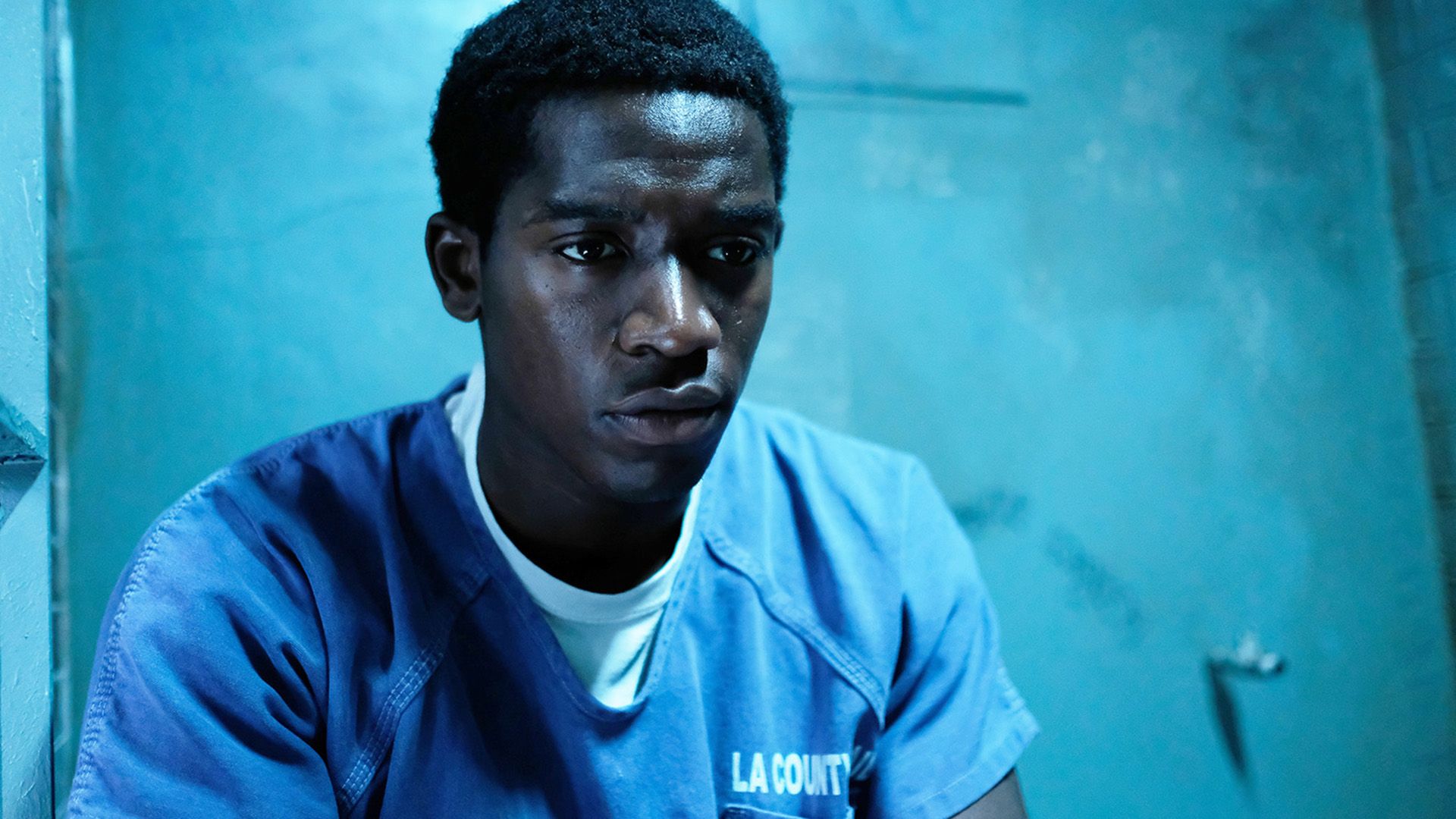 Damson Idris w niebieskiej więziennej koszuli siedzi w celi