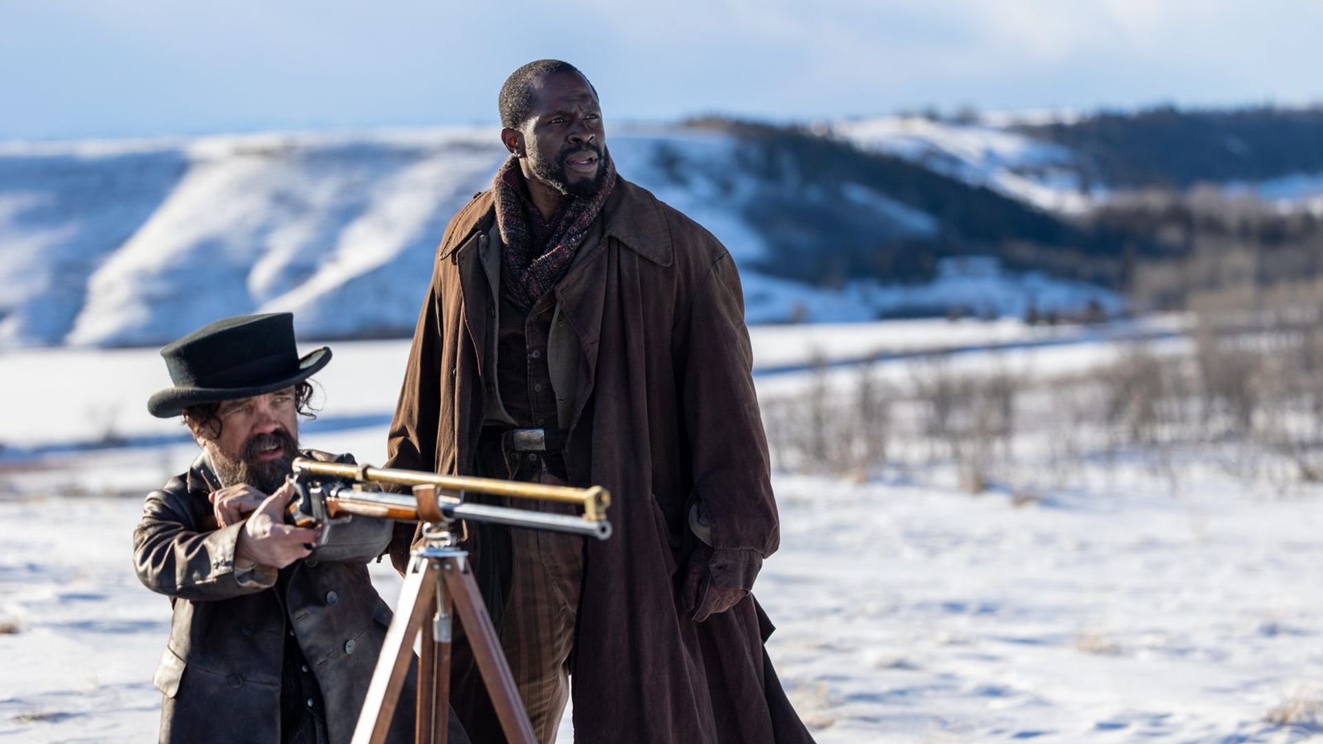 Peter Dinklage i Gbenga Akinnagbe stoją na śniegu, jeden celuje z karabinu zamontowanego na statywie, drugi patrzy w dal