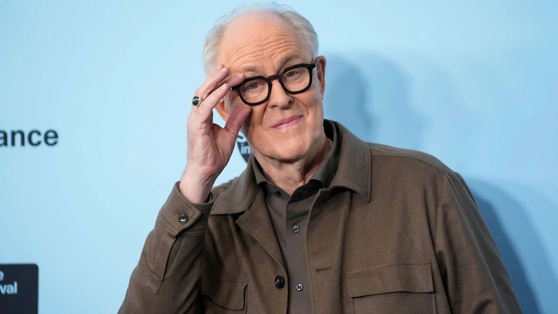 Aktor John Lithgow poprawia okulary w czarnej oprawce