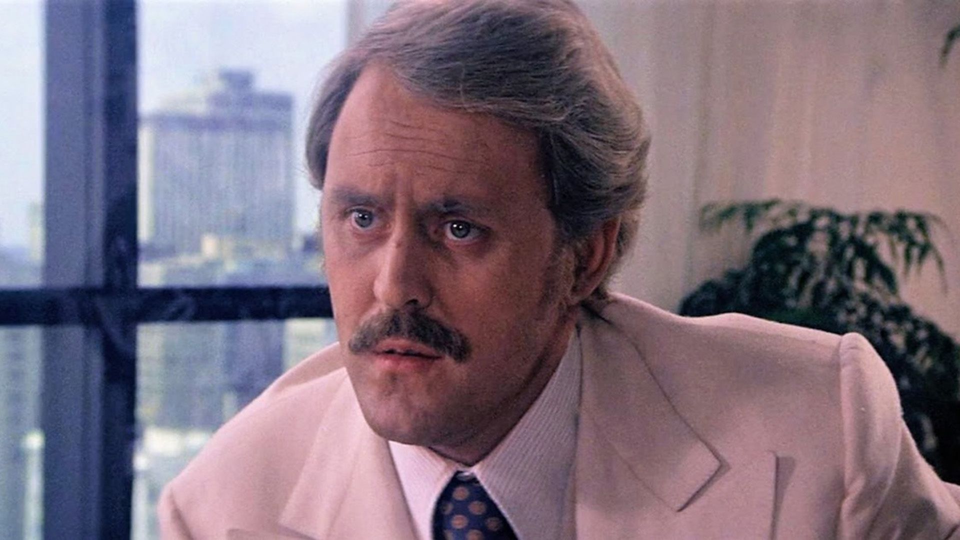 John Lithgow z wąsami i w kremowej marynarce w kadrze z filmu "Obsession"