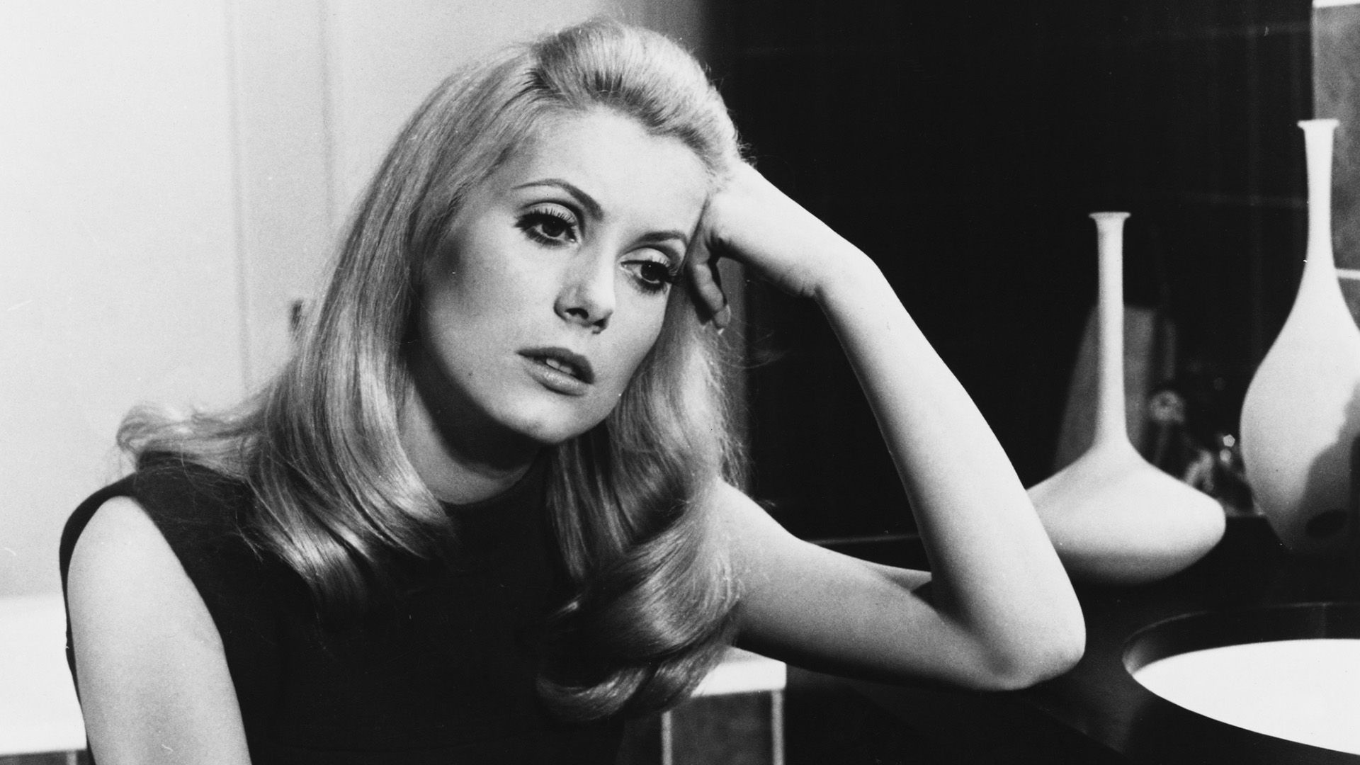 Catherine Deneuve zamyślona opiera się o stół w scenie z filmu 'Belle de Jour'