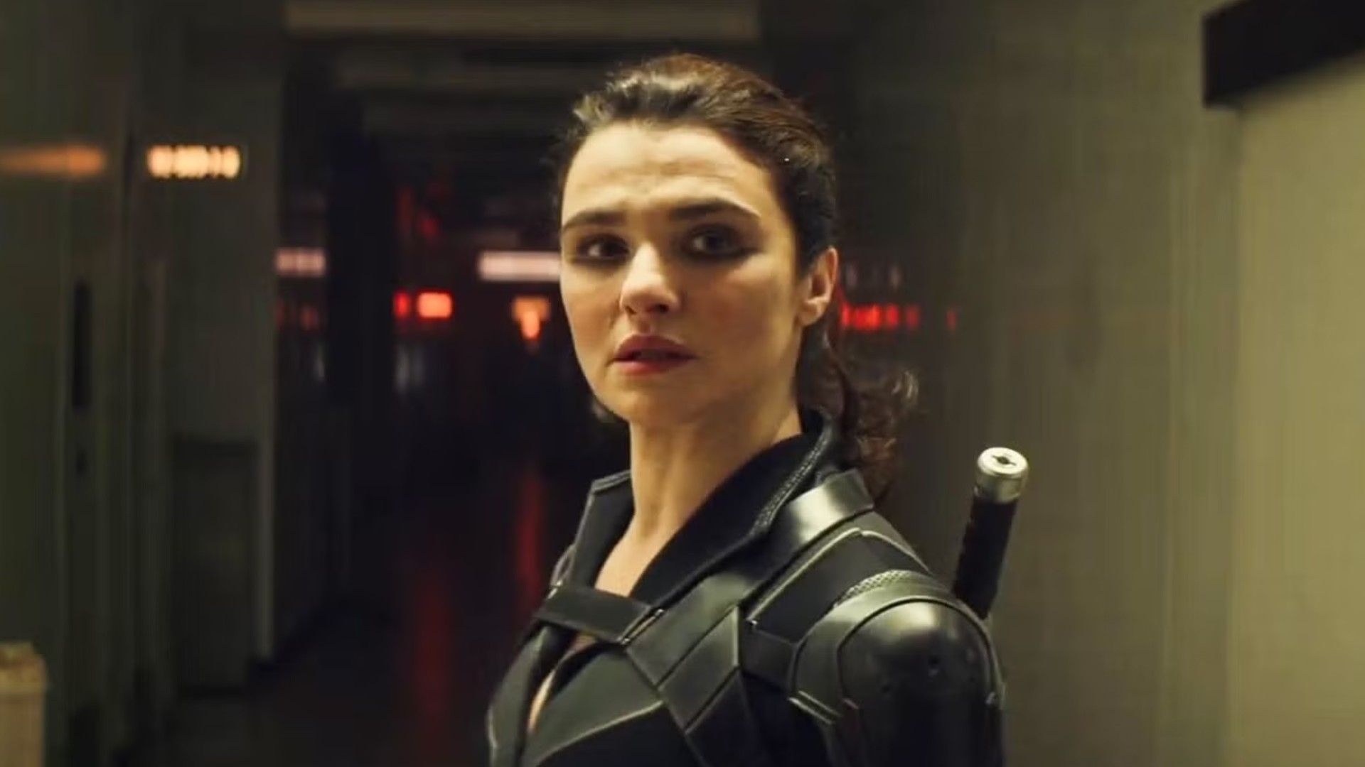 Aktorka Rachel Weisz z włosami spiętymi w kucyk, ubrana w czarny kostium superbohaterki