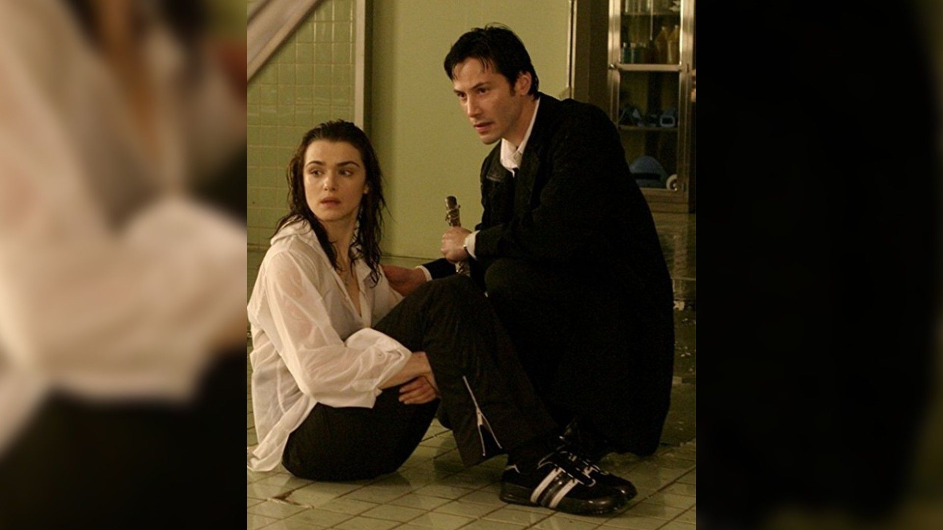 Rachel Weisz i Keanu Reeves siedzący na podłodze obok siebie