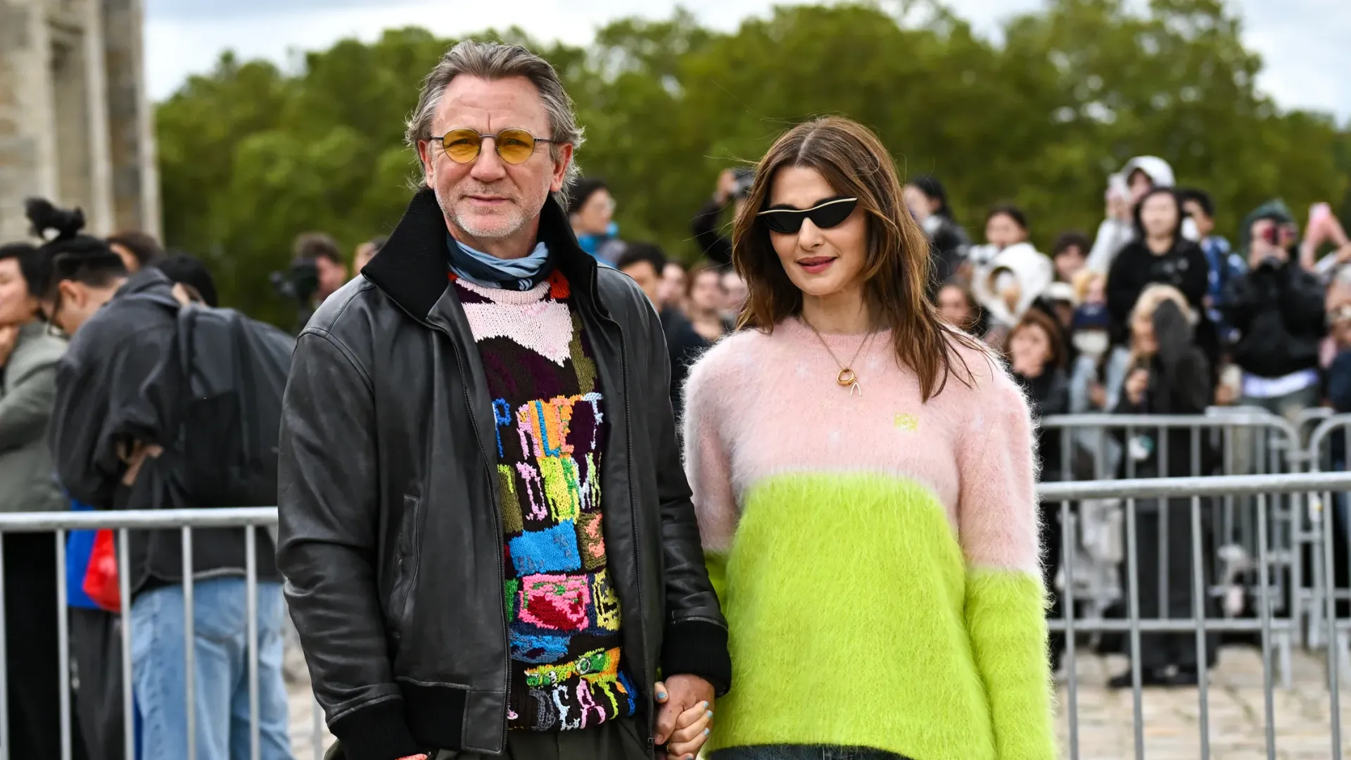Rachel Weisz w biało-zielonym swetrze i Daniel Craig w czarnej skórzanej kurtce i kolorowym swetrze trzymający się za ręce