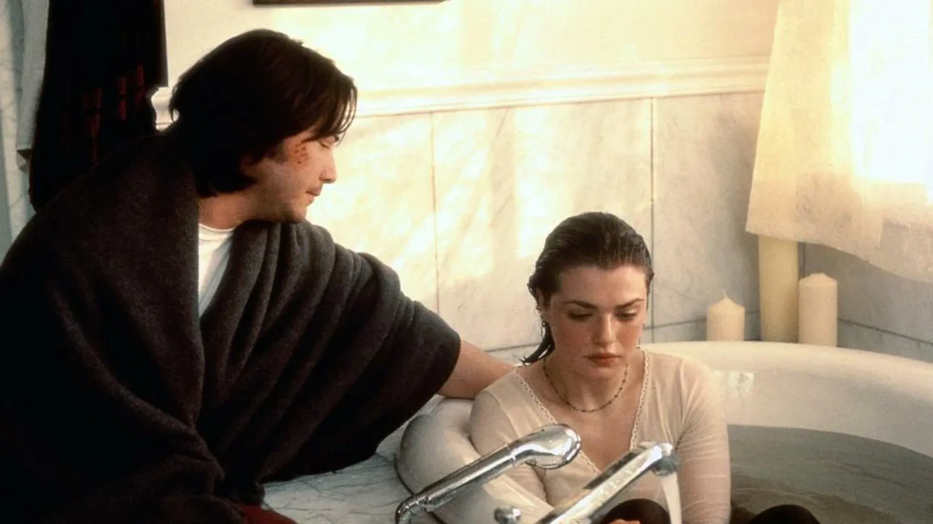 Młoda Rachel Weisz siedzi w wannie w ubraniu, obok niej siedzi młody Keanu Reeves