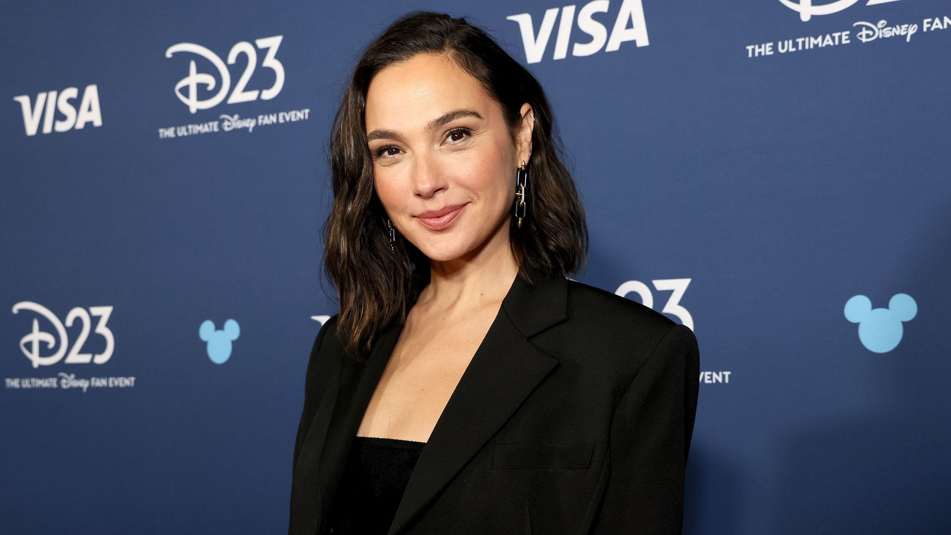 Aktorka Gal Gadot w czarnej kurtce na tle niebieskiego tła