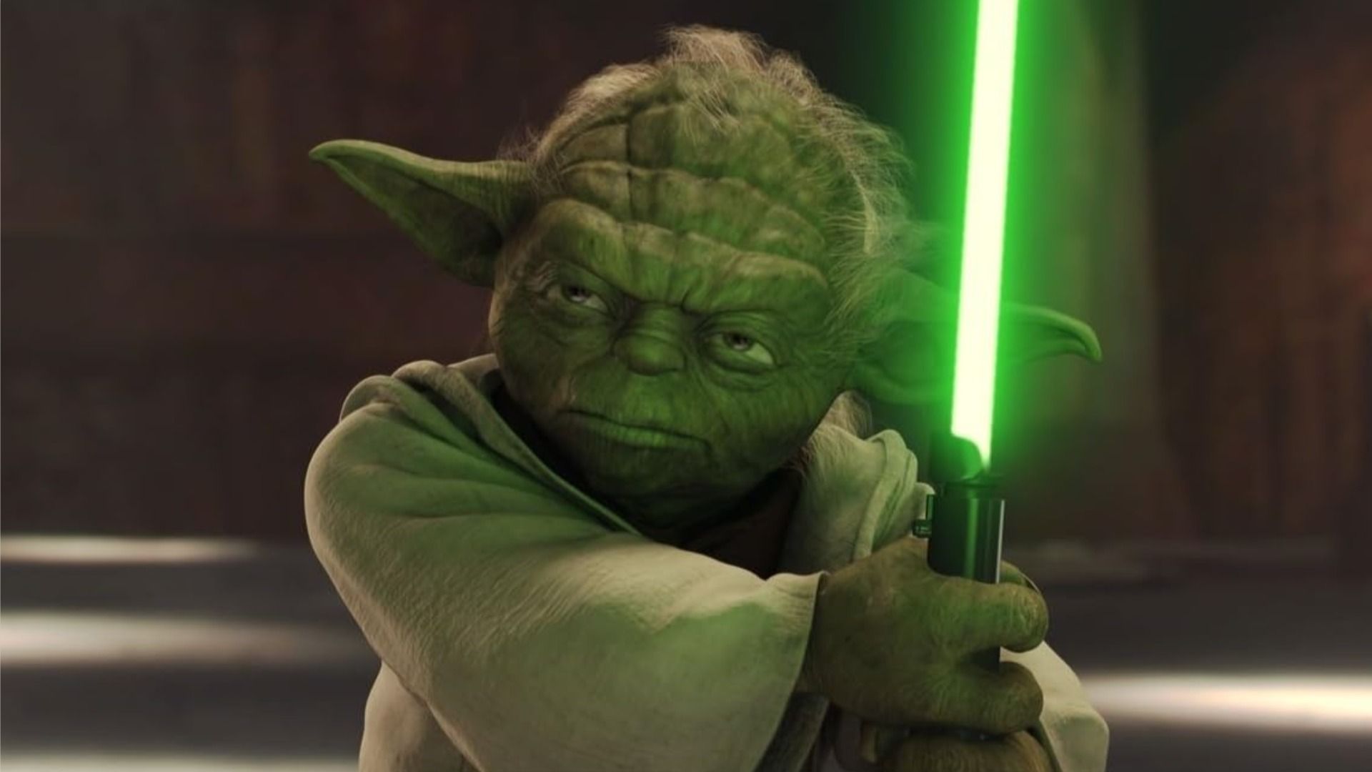Mistrz Yoda trzyma miecz świetlny i patrzy surowo w bok na brązowym tle