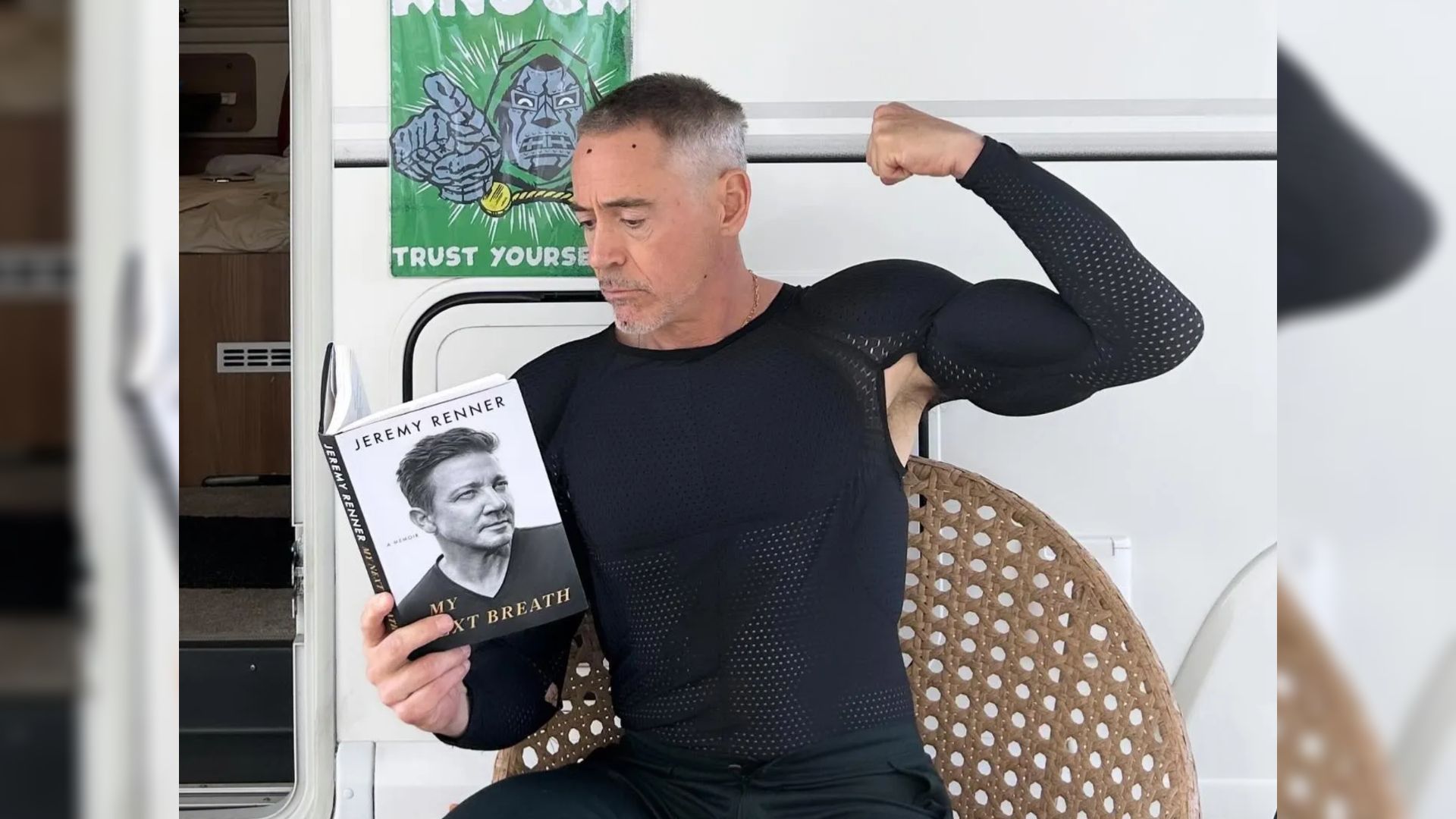 Aktor Robert Downey Jr. w obcisłym ubraniu siedzi przy przyczepie i trzyma książkę w rękach