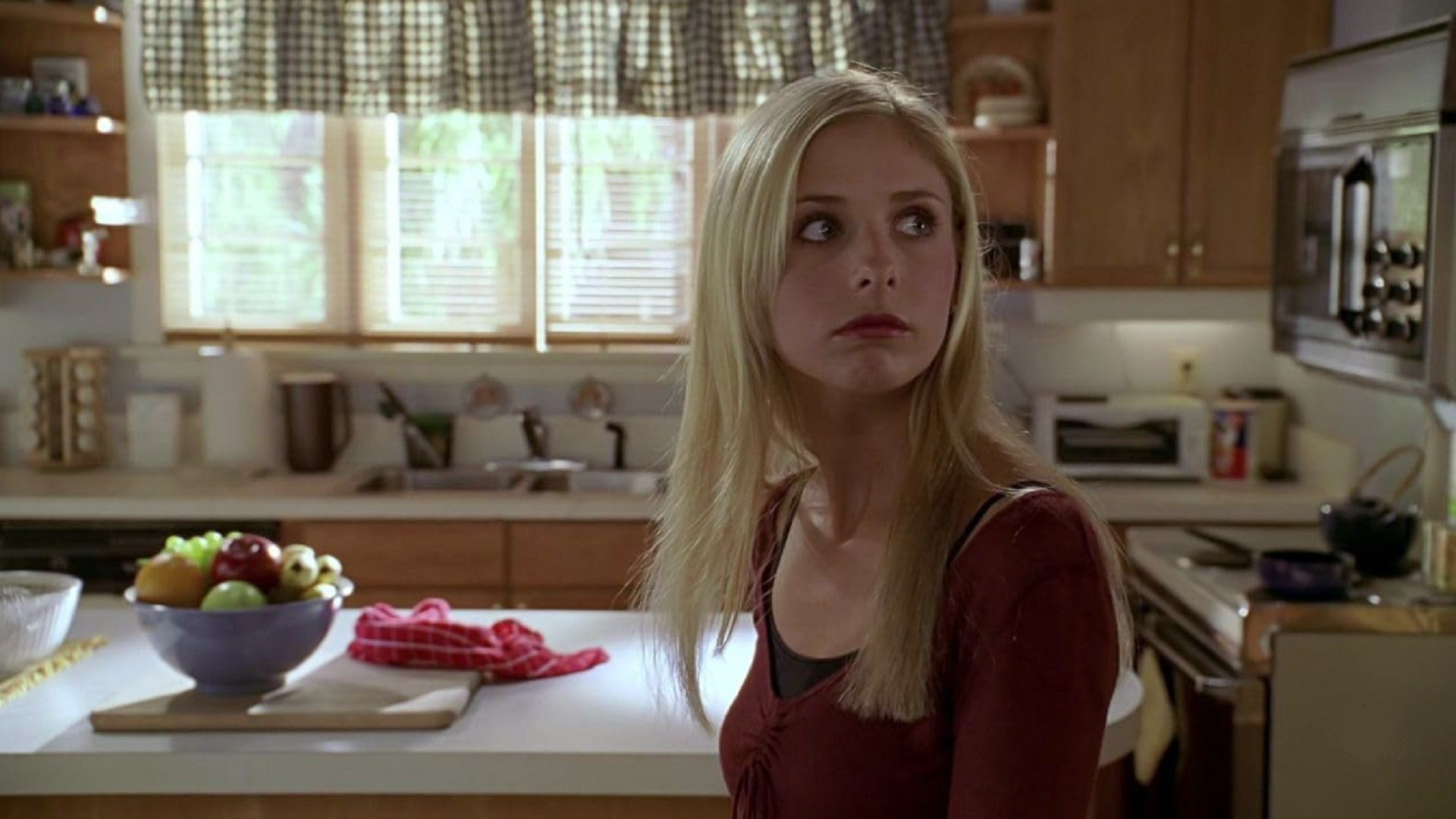 Sarah Michelle Gellar jako Buffy patrzy na bok, oceniając w kuchni