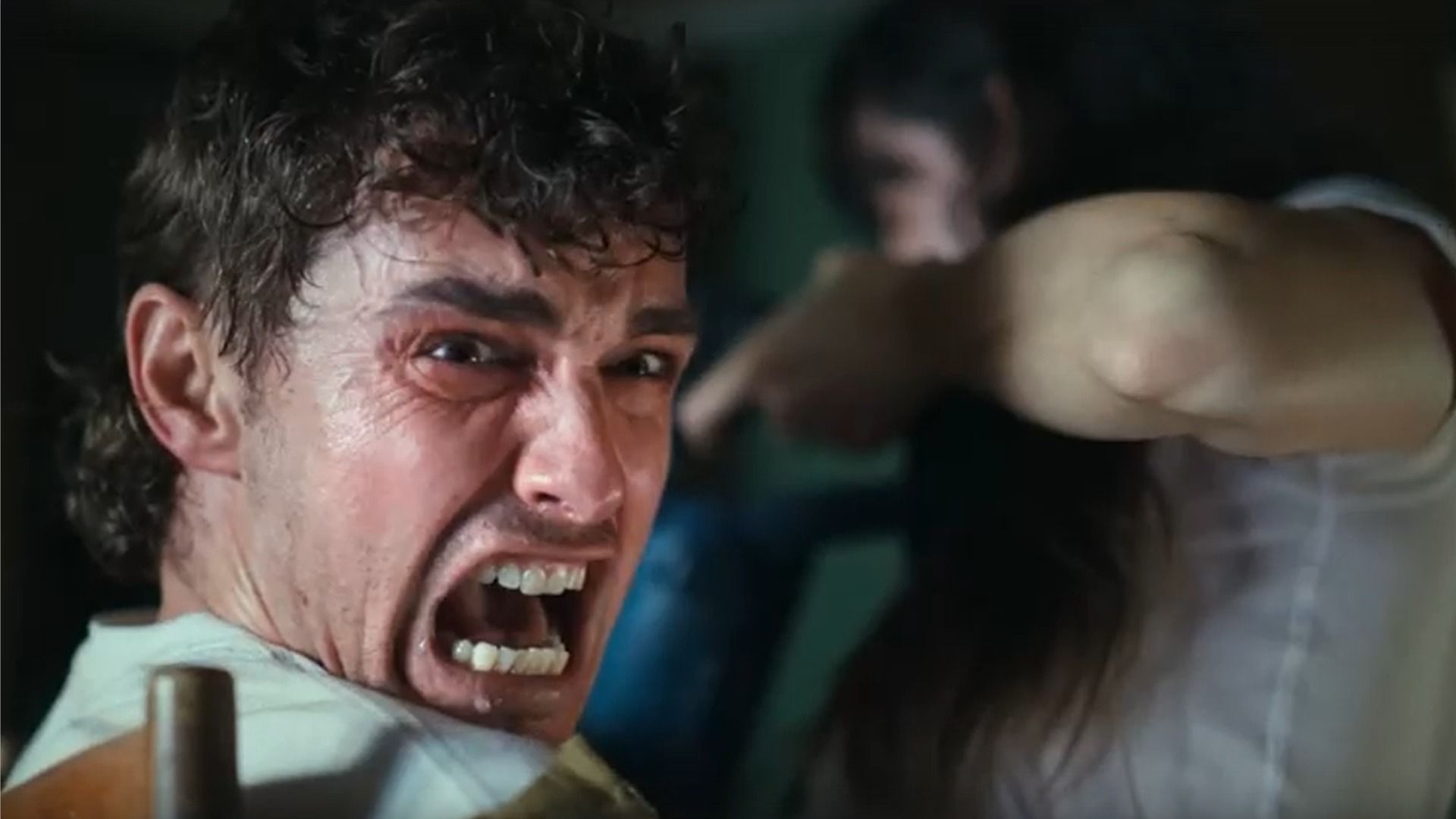 Aktor Dave Franco patrzy w bok i krzyczy, siedząc na krześle obok aktorki Alison Brie