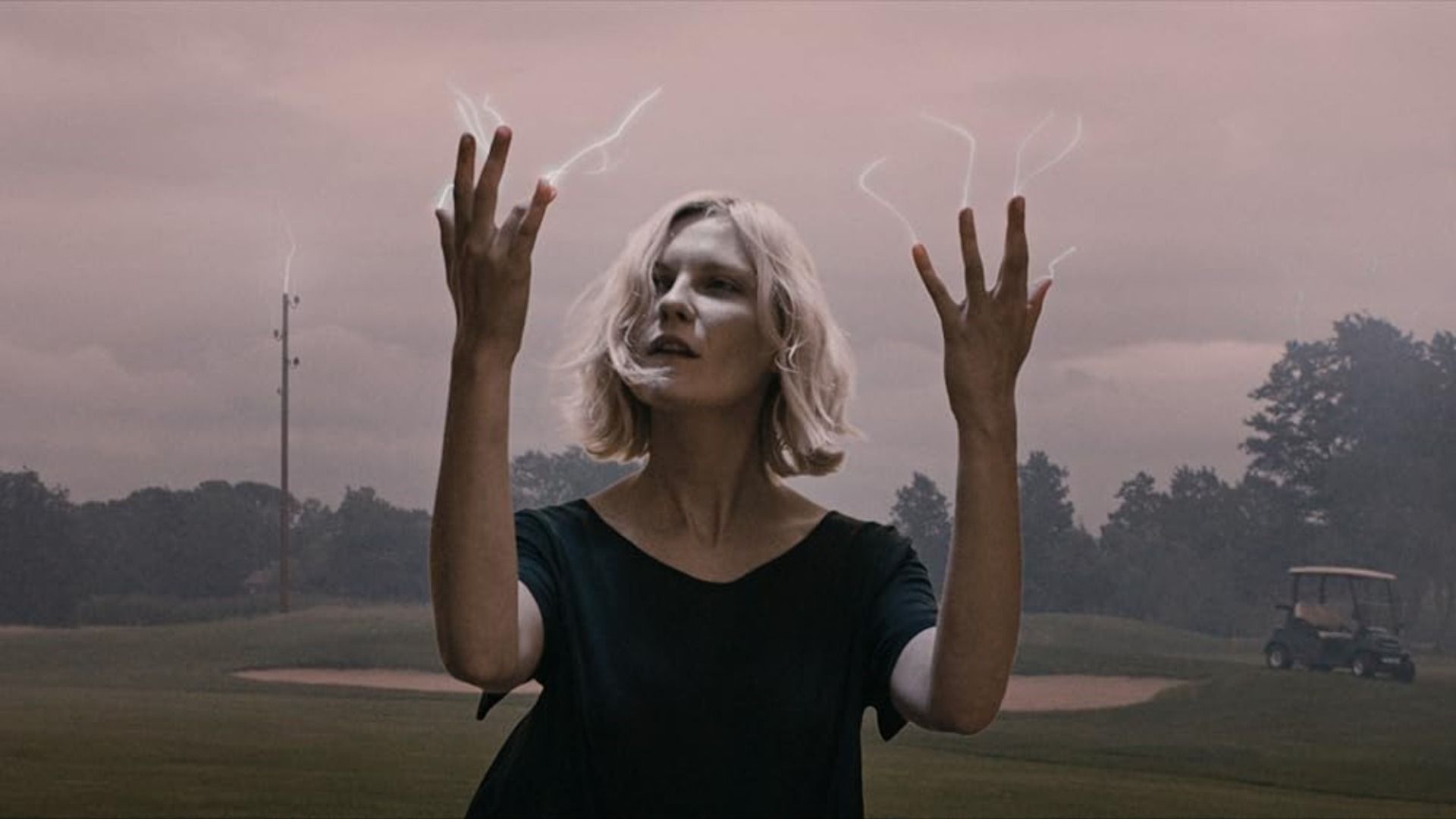 Aktorka Kirsten Dunst patrzy na swoje palce, z których wychodzą małe błyskawice