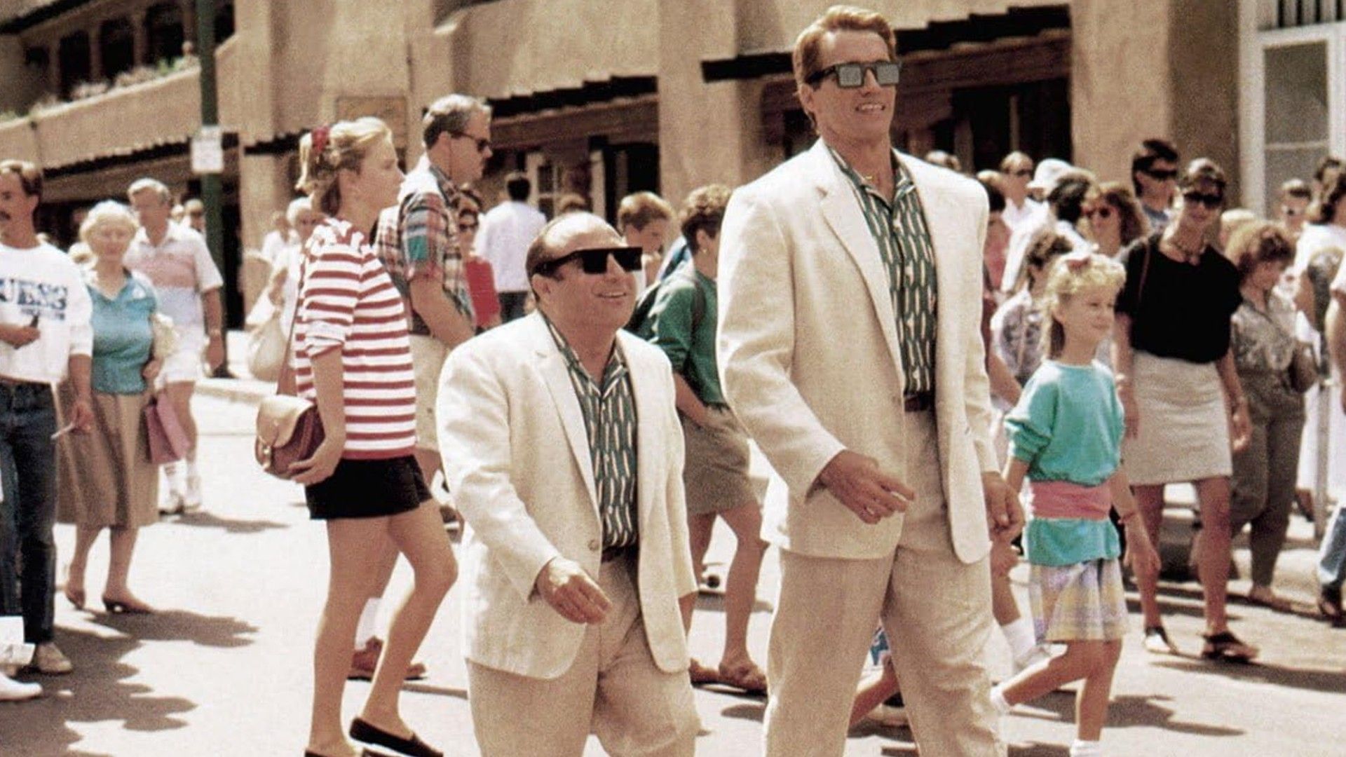 Danny DeVito i Arnold Schwarzenegger w białych garniturach idący ramię w ramię