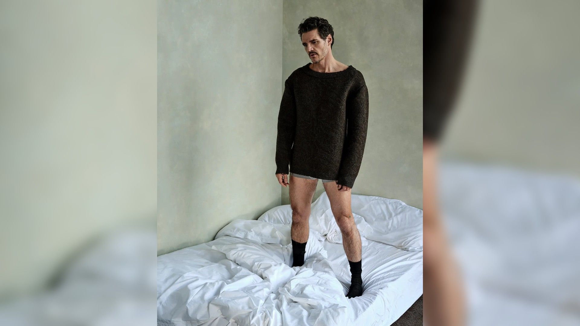 Pedro Pascal stoi na łóżku w swetrze i bieliźnie