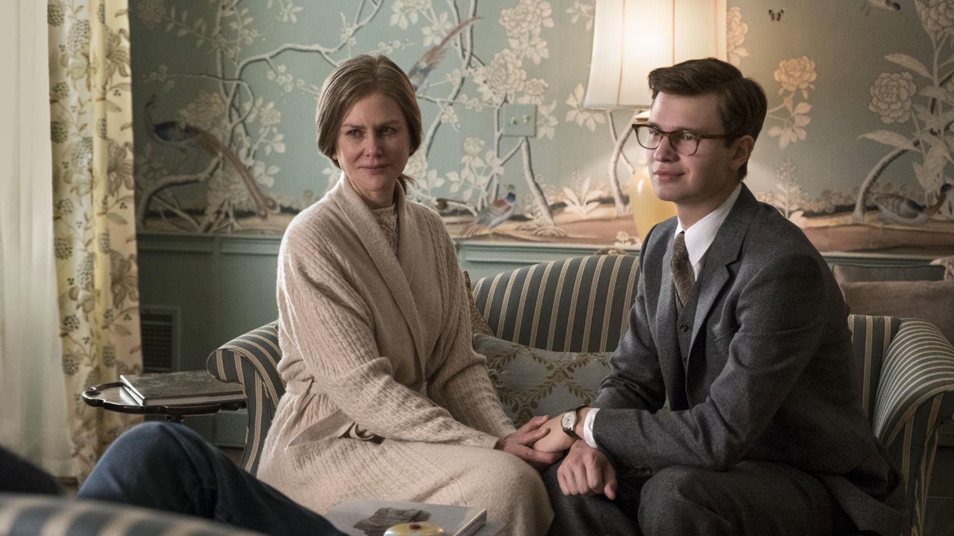 Aktorka Nicole Kidman w białej sukience i aktor Ansel Elgort w szarej marynarce siedzący na kanapie