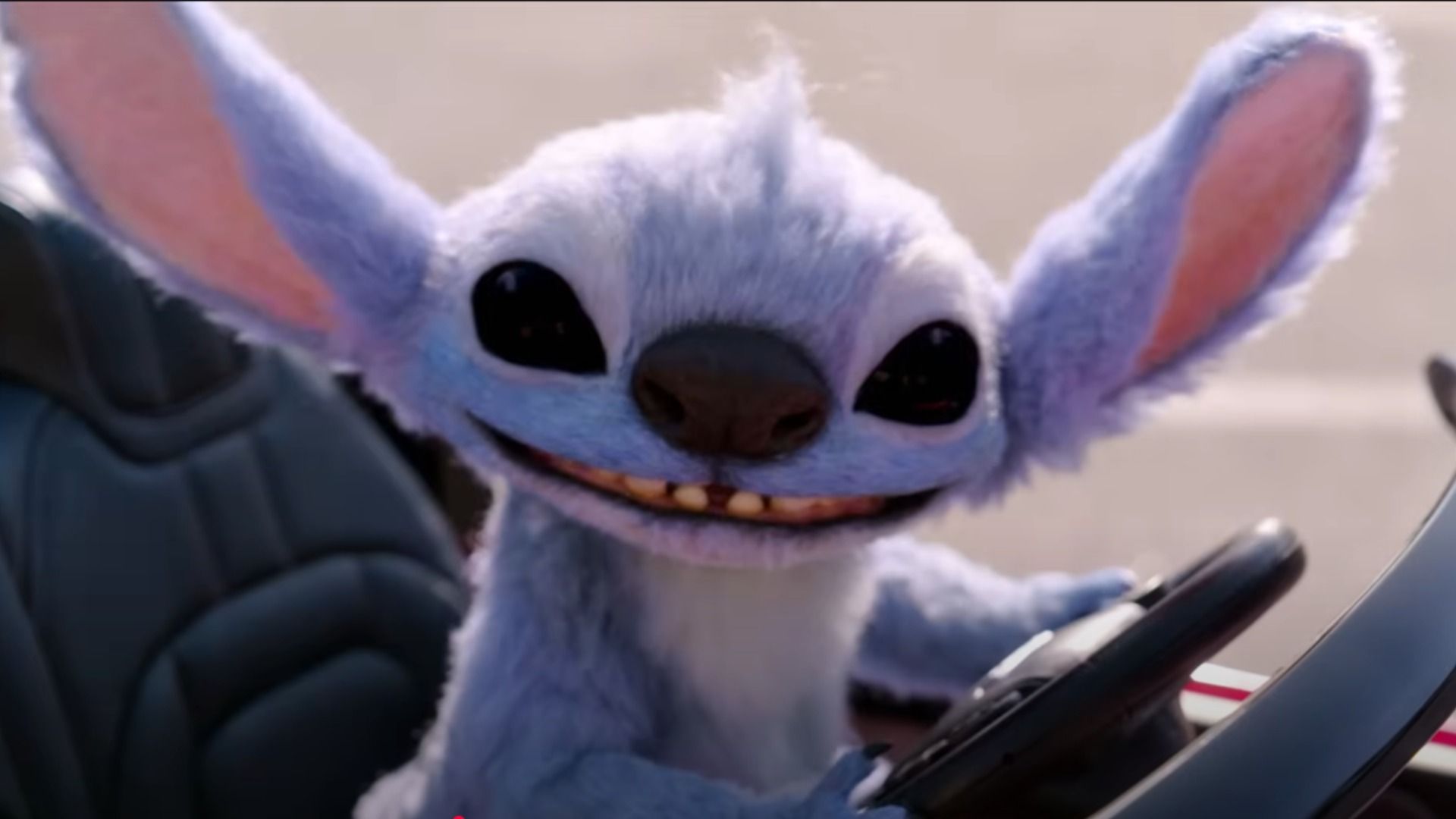 Niebieski kosmita Stitch siedzi za kierownicą małego samochodu i uśmiecha się
