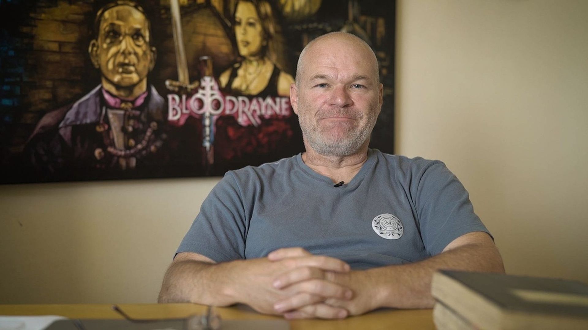 Reżyser Uwe Boll na tle plakatu filmu BloodRayne