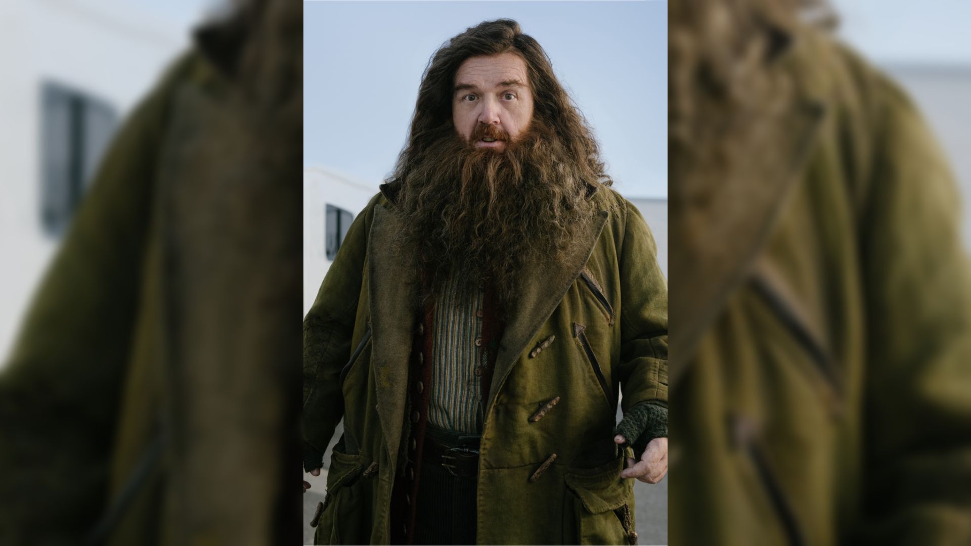 Aktor Nick Frost w zielonym płaszczu z długą brodą i długimi włosami