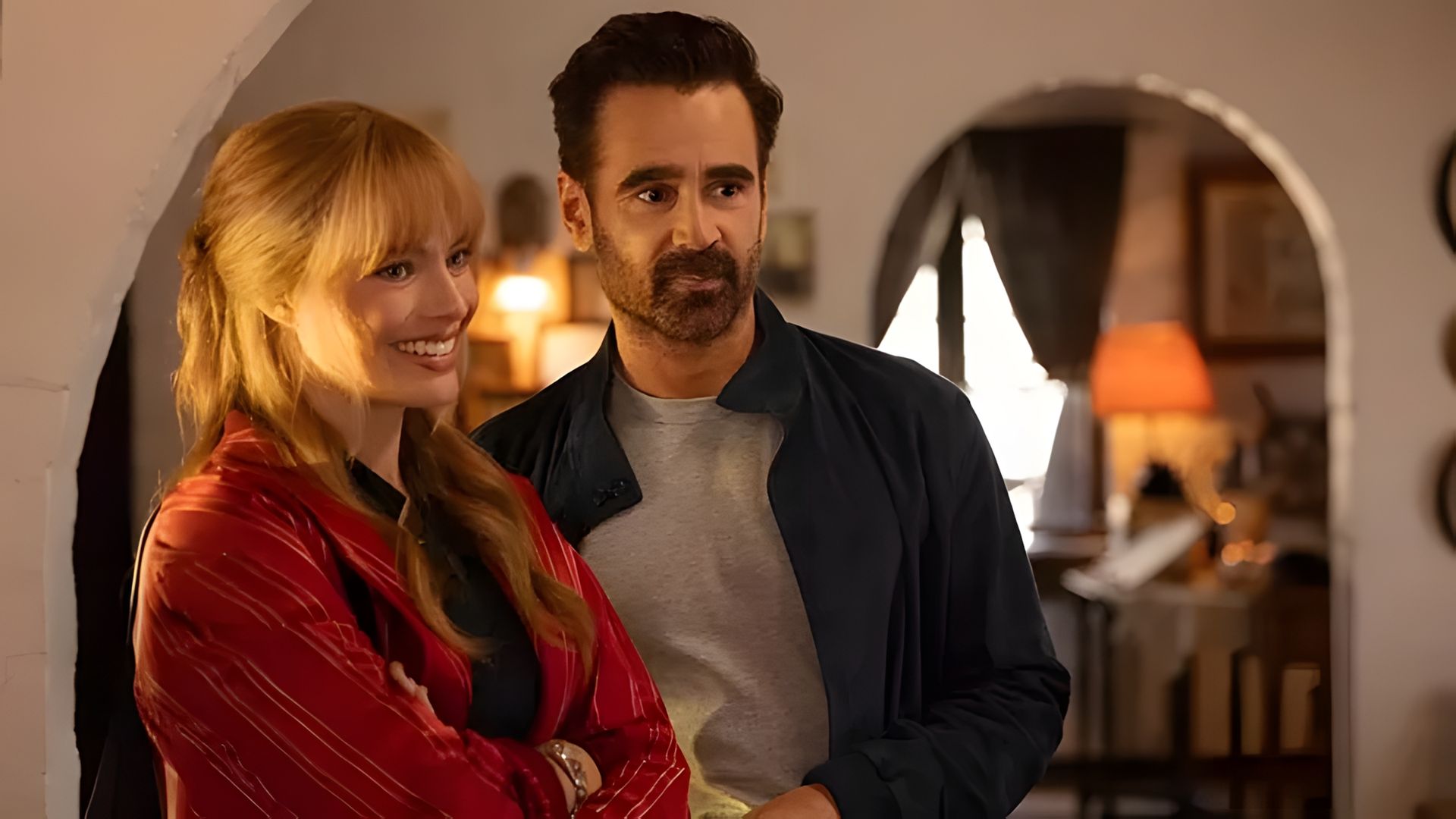 Margot Robbie i Colin Farrell stojący obok siebie w przytulnym pokoju z ciepłym, miękkim oświetleniem