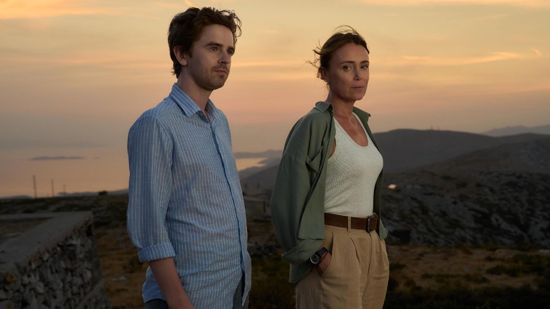 Aktor Freddie Highmore w niebieskiej koszuli i aktorka Keeley Hawes w białej koszulce na ramiączkach stojący na tle gór
