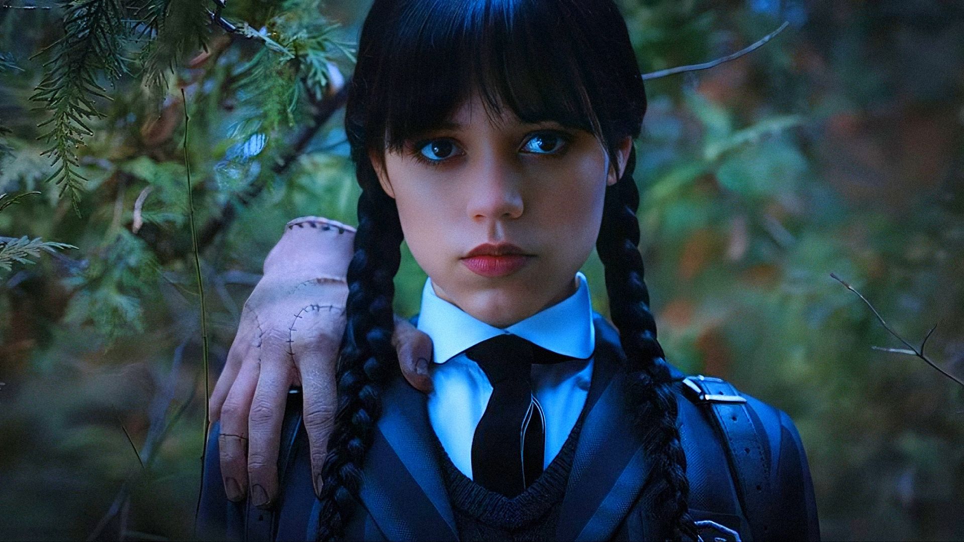 Aktorka Jenna Ortega w szkolnym mundurku z ręką na ramieniu patrzy w kamerę
