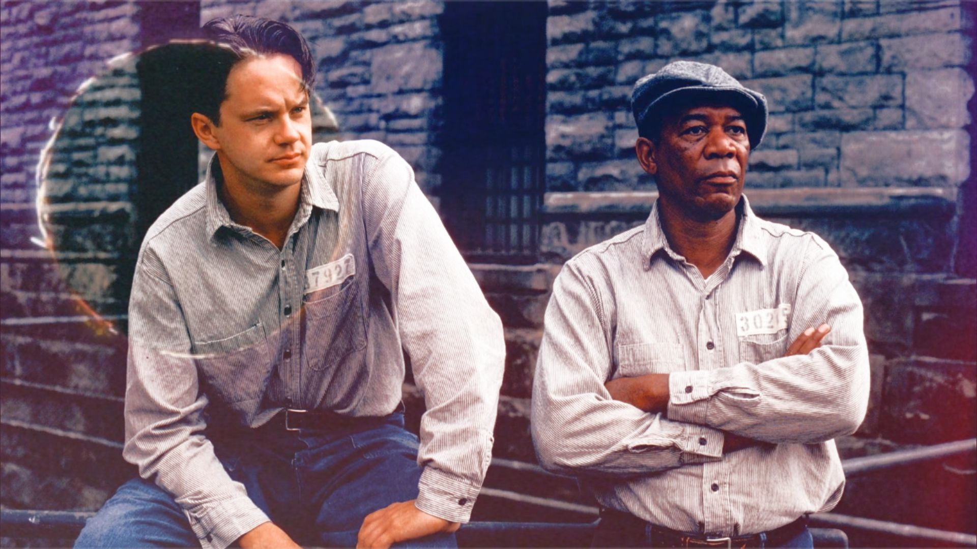 Aktorzy Tim Robbins i Morgan Freeman w więziennych uniformach siedzący przy kamiennym murze