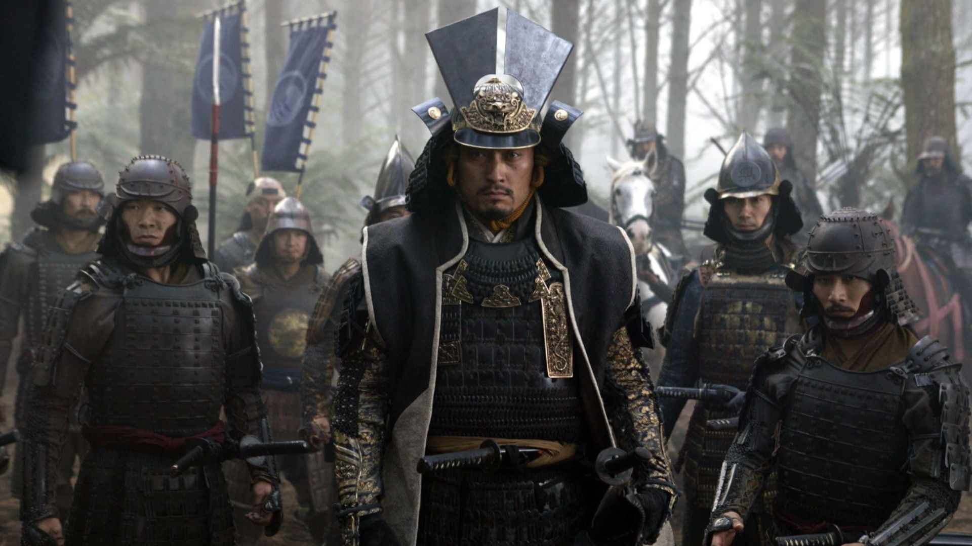 Aktor Ken Watanabe w ciemnej zbroi samuraja stoi otoczony przez innych samurajów