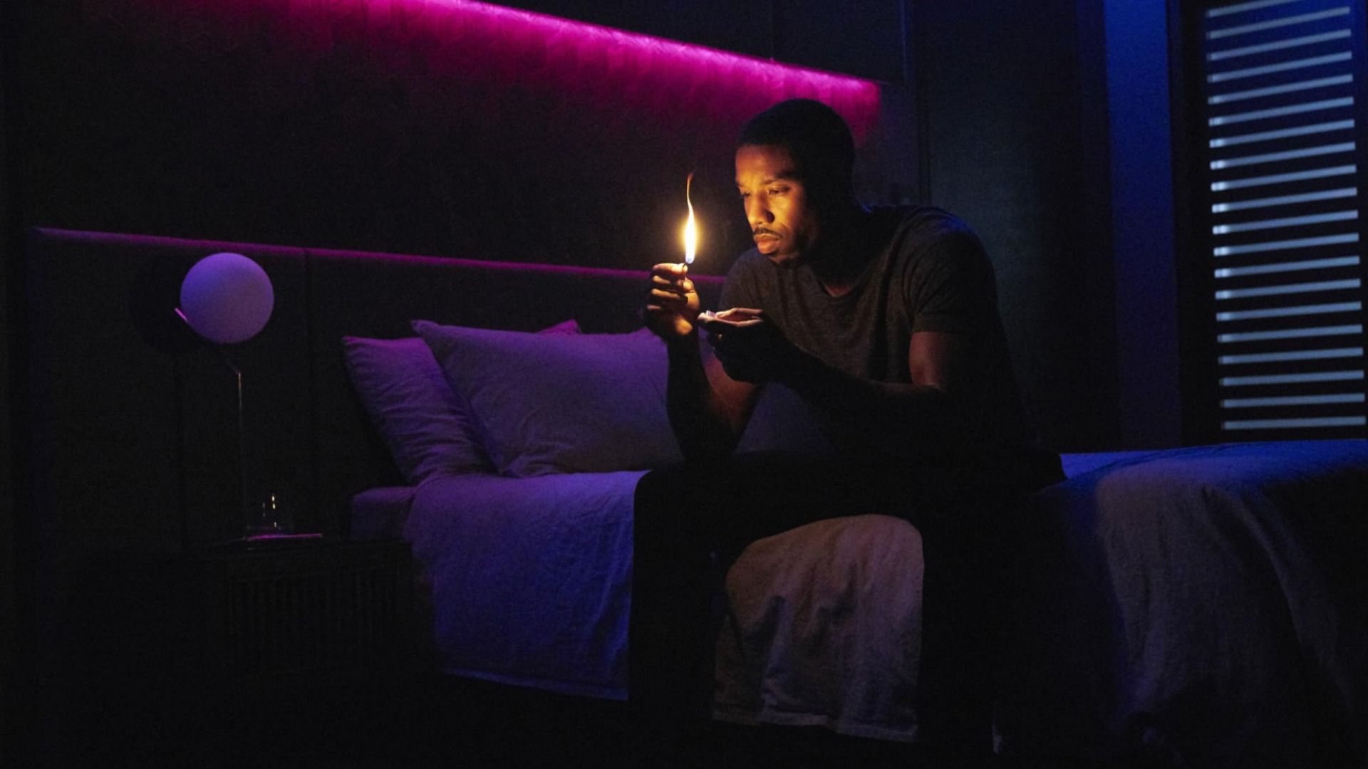 Aktor Michael B. Jordan siedzi na łóżku z zapałką w rękach