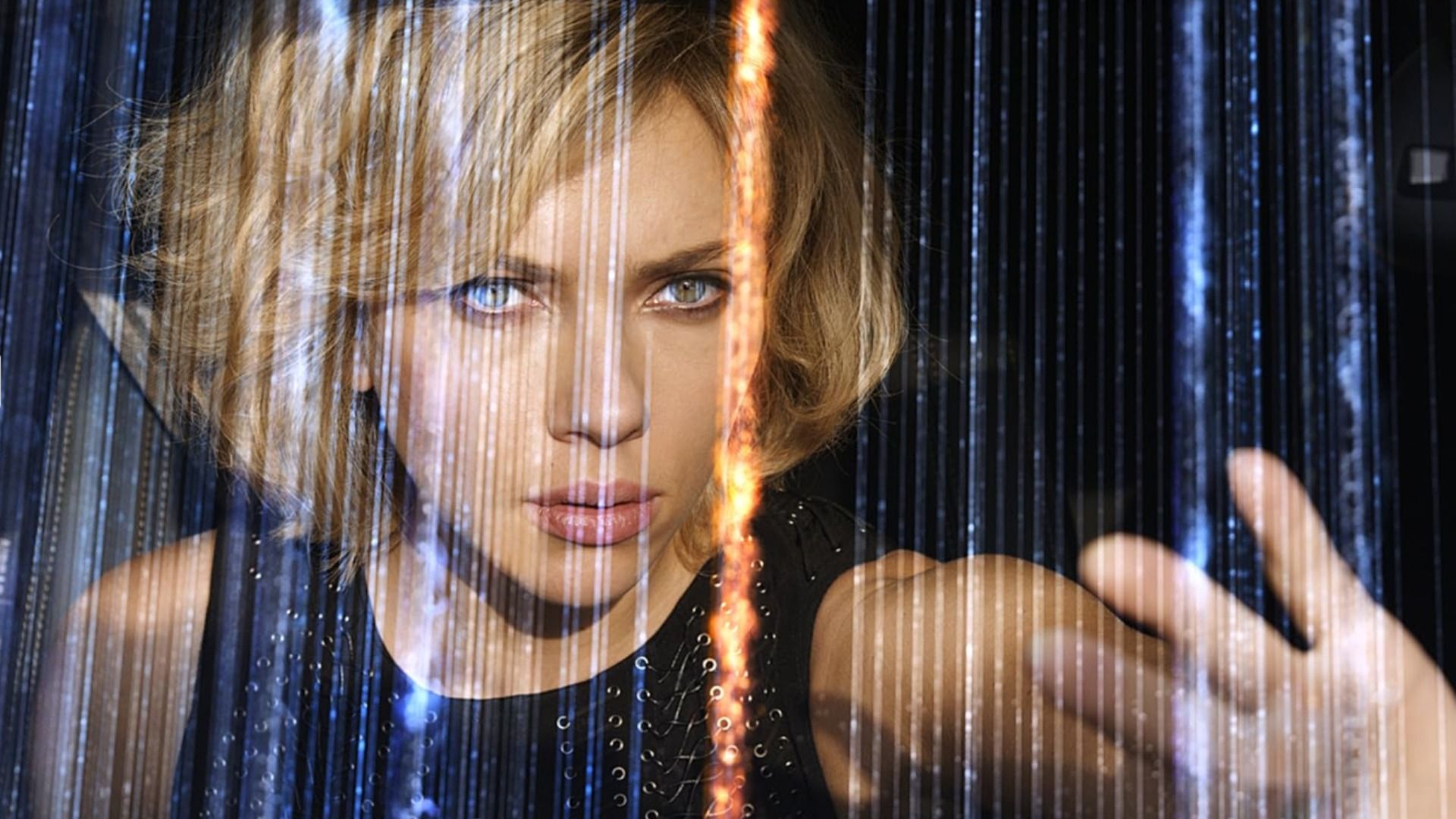 Aktorka Scarlett Johansson w czarnej sukience z uniesioną ręką pośród migoczących linii