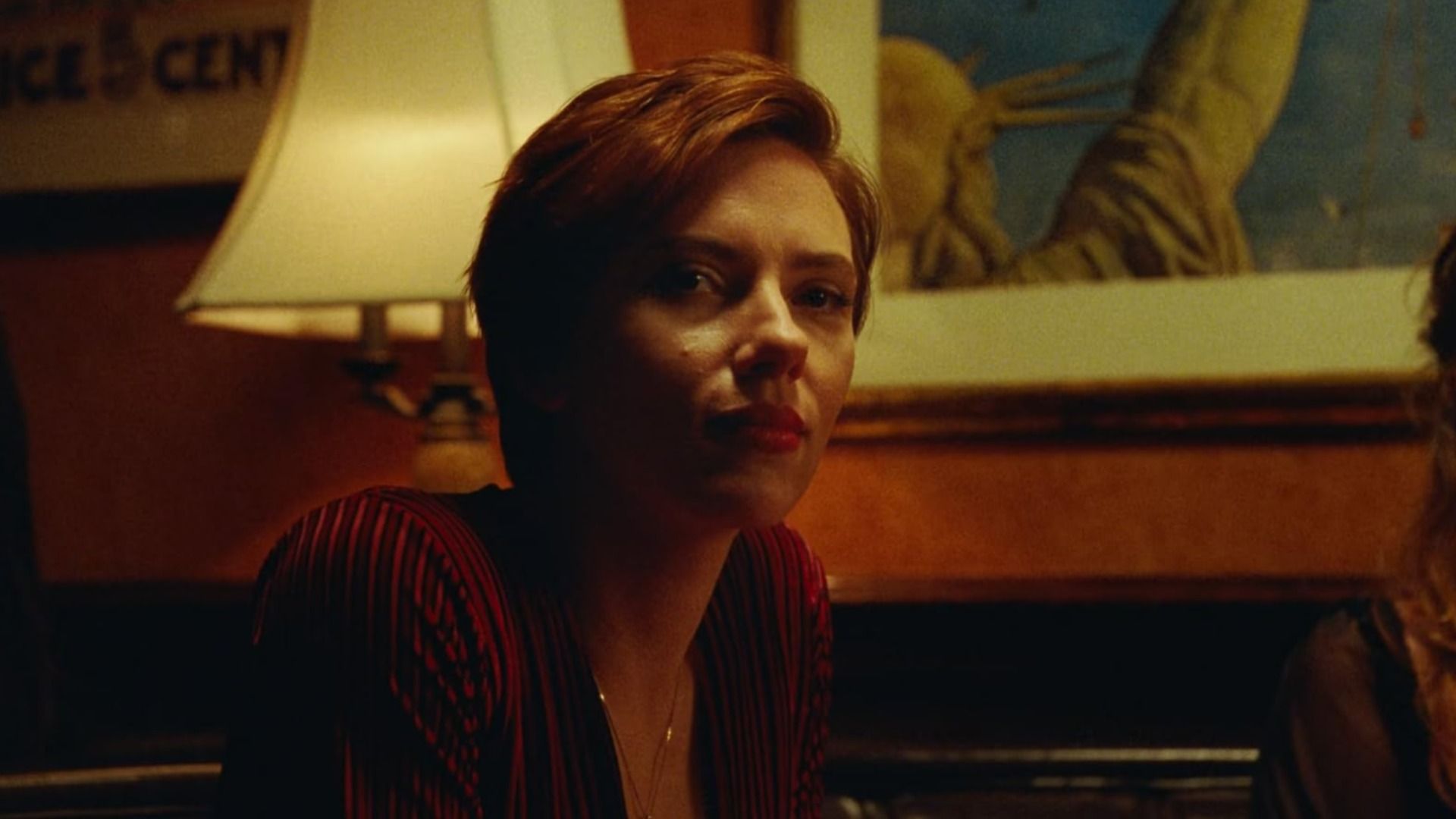 Aktorka Scarlett Johansson w czerwonej bluzce siedzi przy lampie