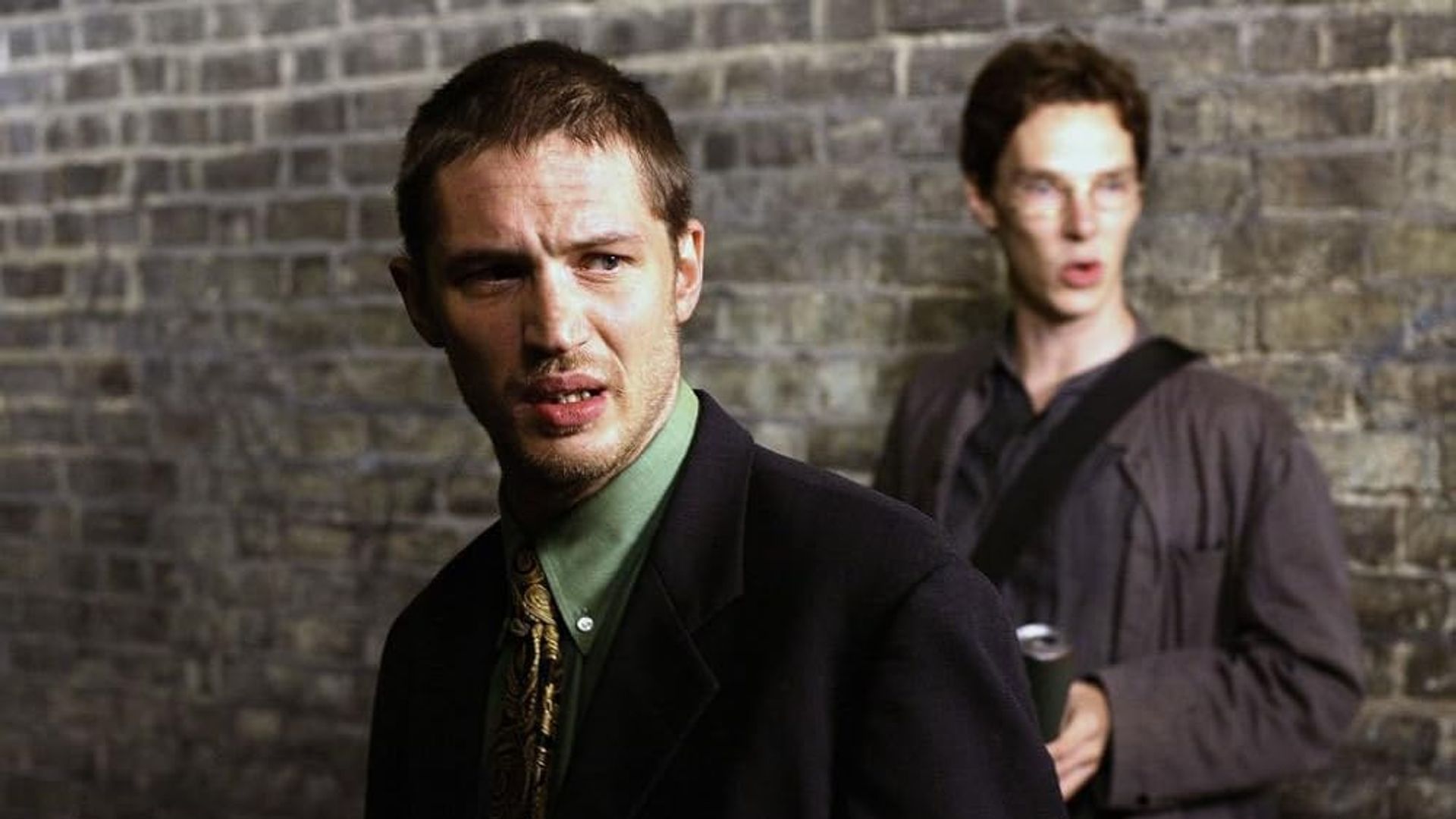 Młody Tom Hardy i Benedict Cumberbatch stojący przy ceglastej ścianie
