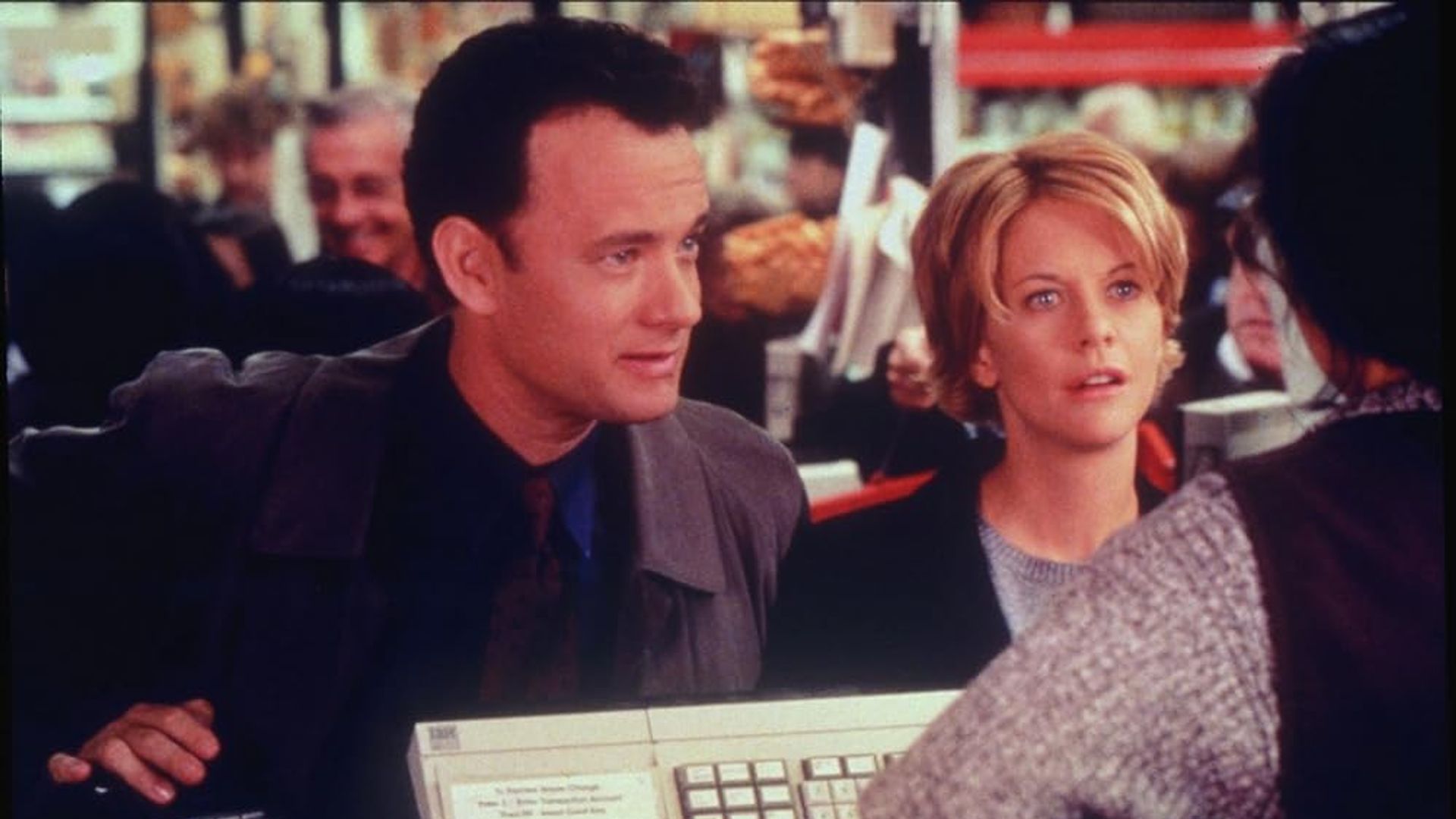 Tom Hanks i Meg Ryan stojący przy kasie w sklepie i rozmawiający z kasjerem