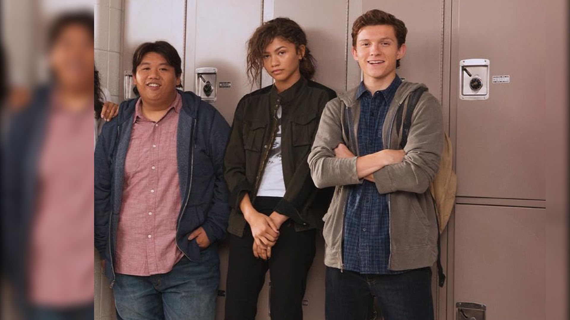 Aktorzy Jacob Batalon, Zendaya i Tom Holland w casualowych ubraniach stojący przy szkolnych szafkach