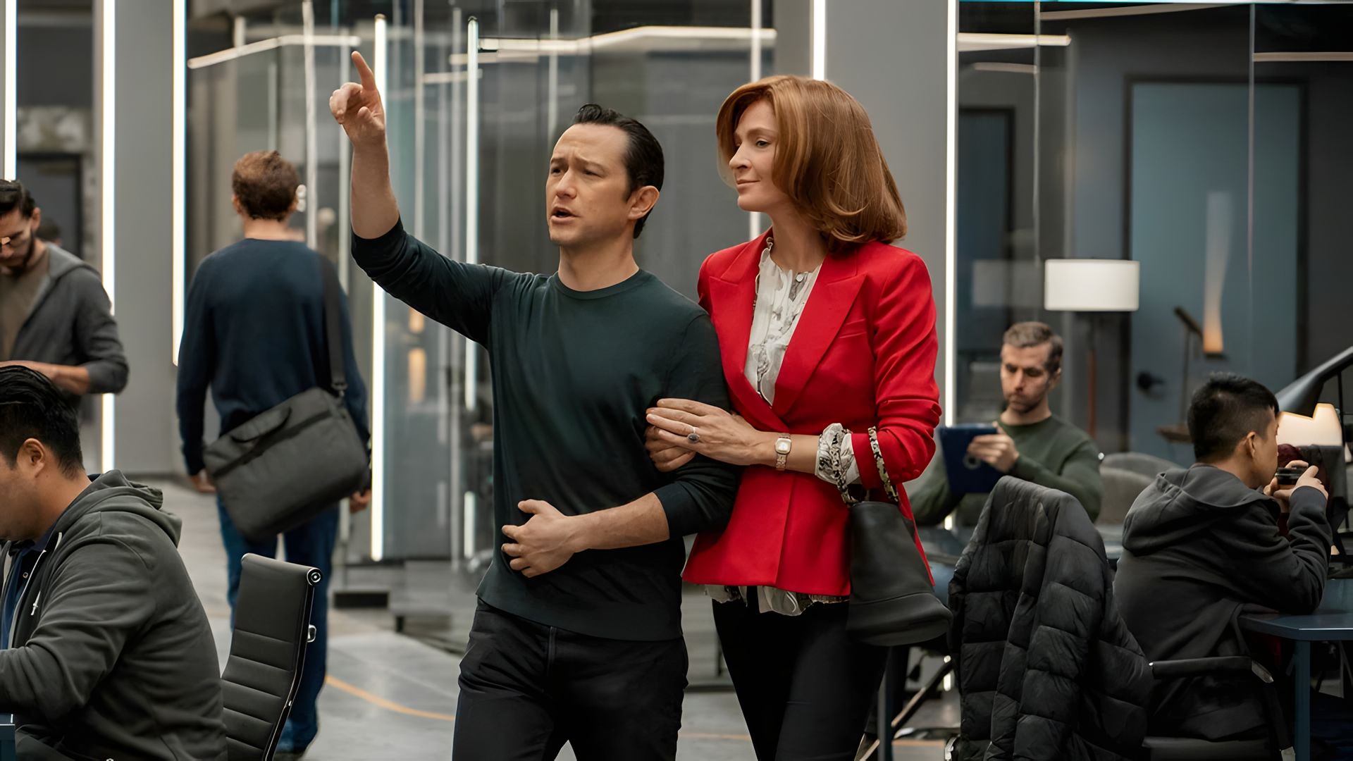 Joseph Gordon-Levitt w ciemnym ubraniu wskazuje do przodu, podczas gdy Uma Thurman w czerwonej kurtce trzyma go za ramię
