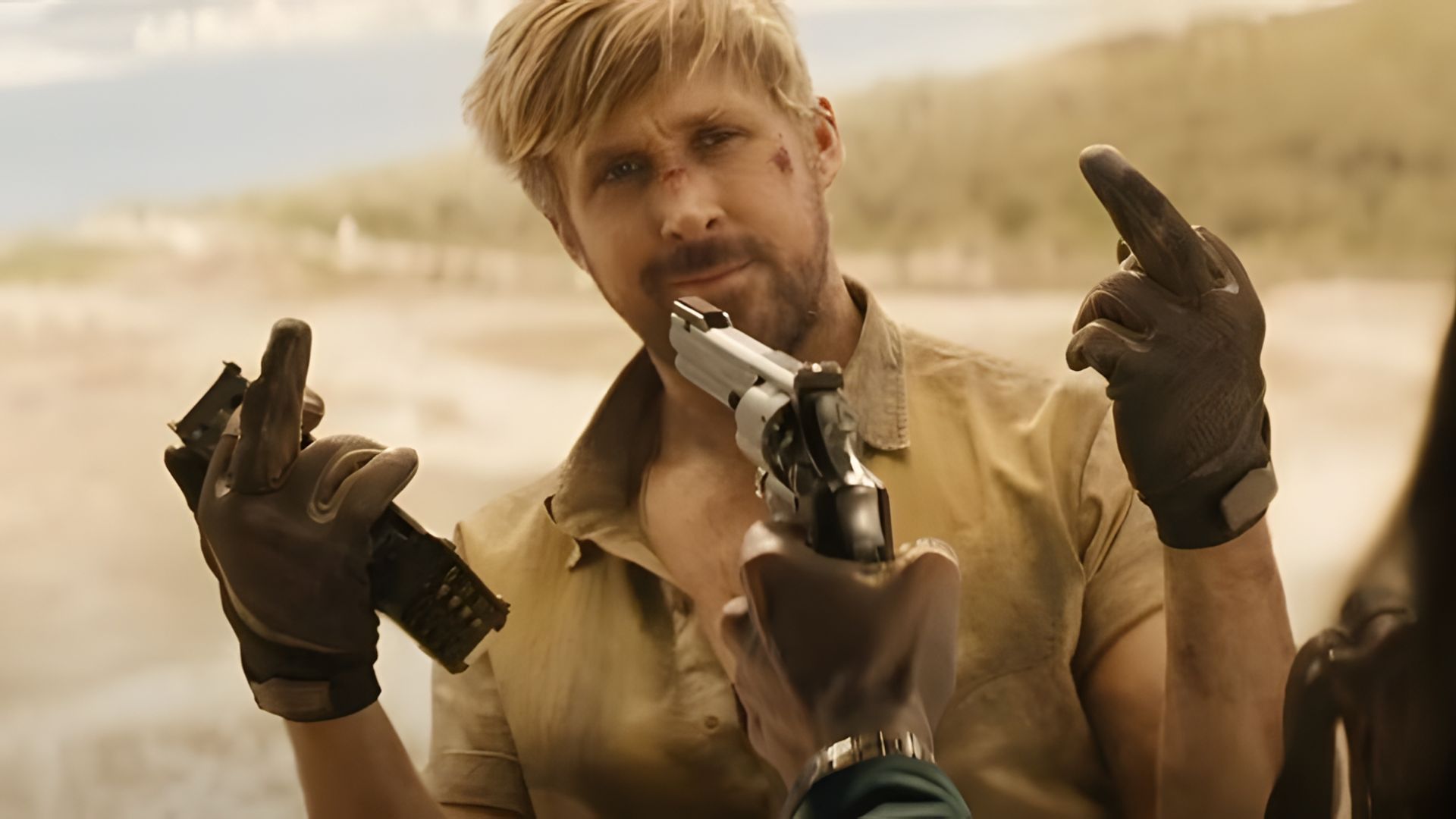 Ryan Gosling z posiniaczoną twarzą pokazuje nieprzyzwoity gest, podczas gdy broń jest wycelowana w jego twarz