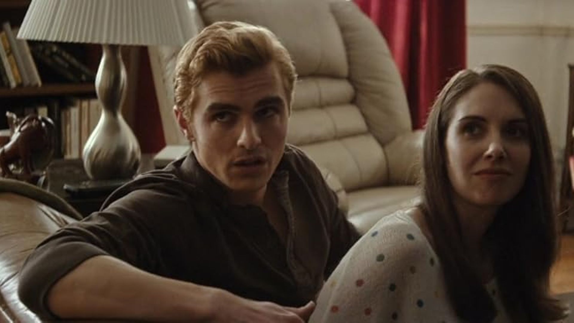 Alison Brie i Dave Franco siedzący na kanapie, odwróceni w połowie w stronę kamery