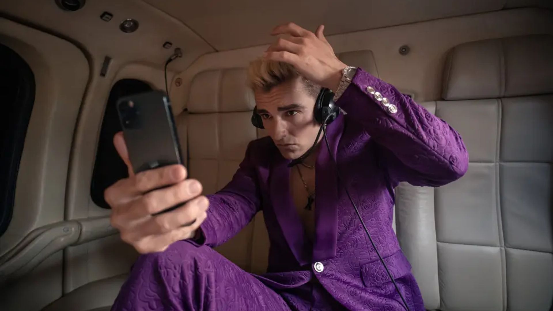 Dave Franco w fioletowym garniturze patrzy na telefon, scena z serialu The Afterparty