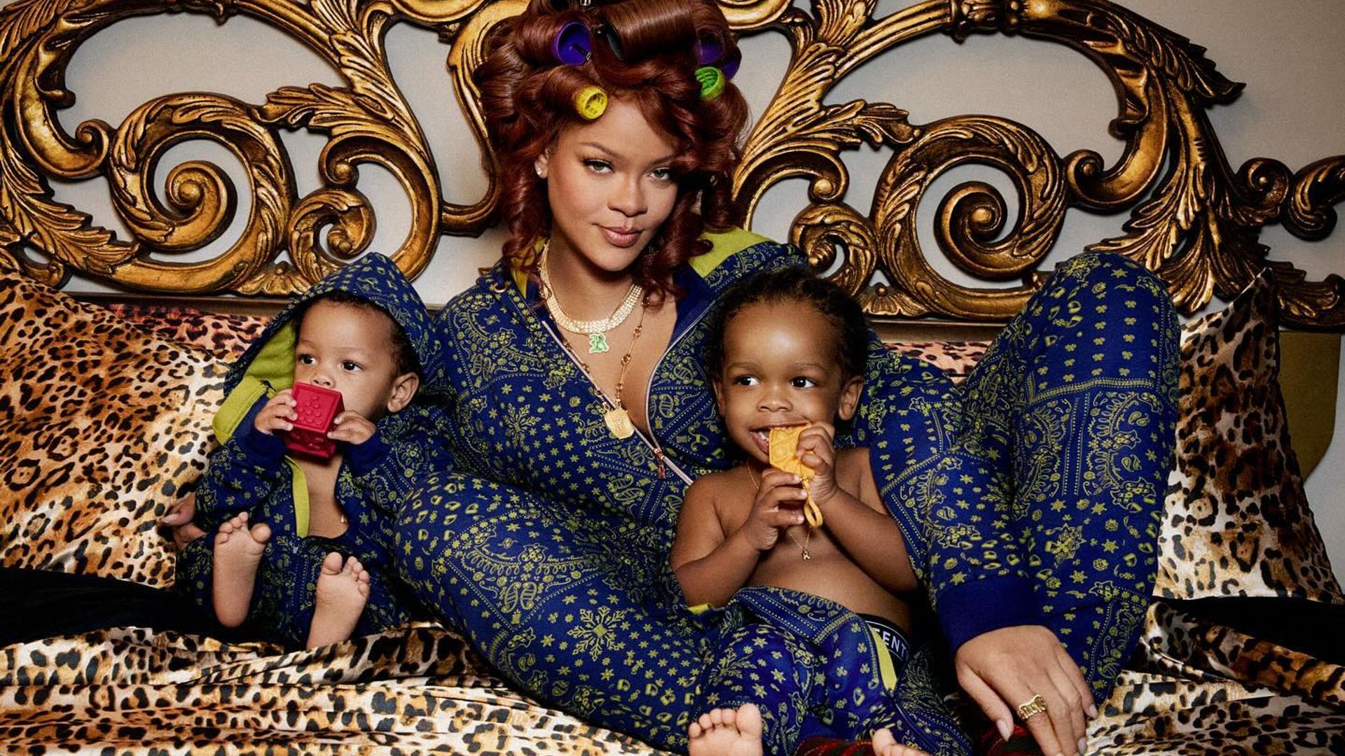 Rihanna w jedwabnej piżamie leżąca na łóżku i przytulająca synów, kadr z sesji zdjęciowej