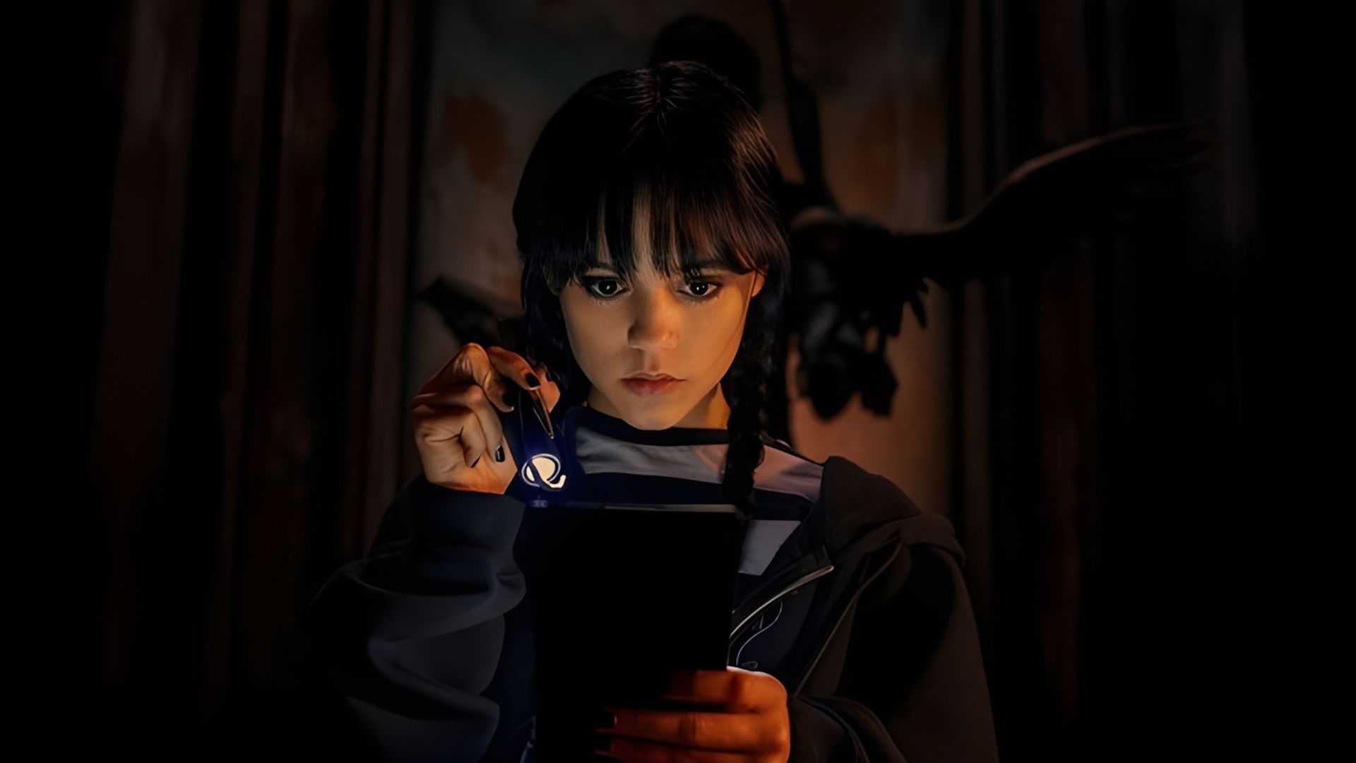 Jenna Ortega jako Wednesday Addams trzymająca latarkę i patrząca na książkę