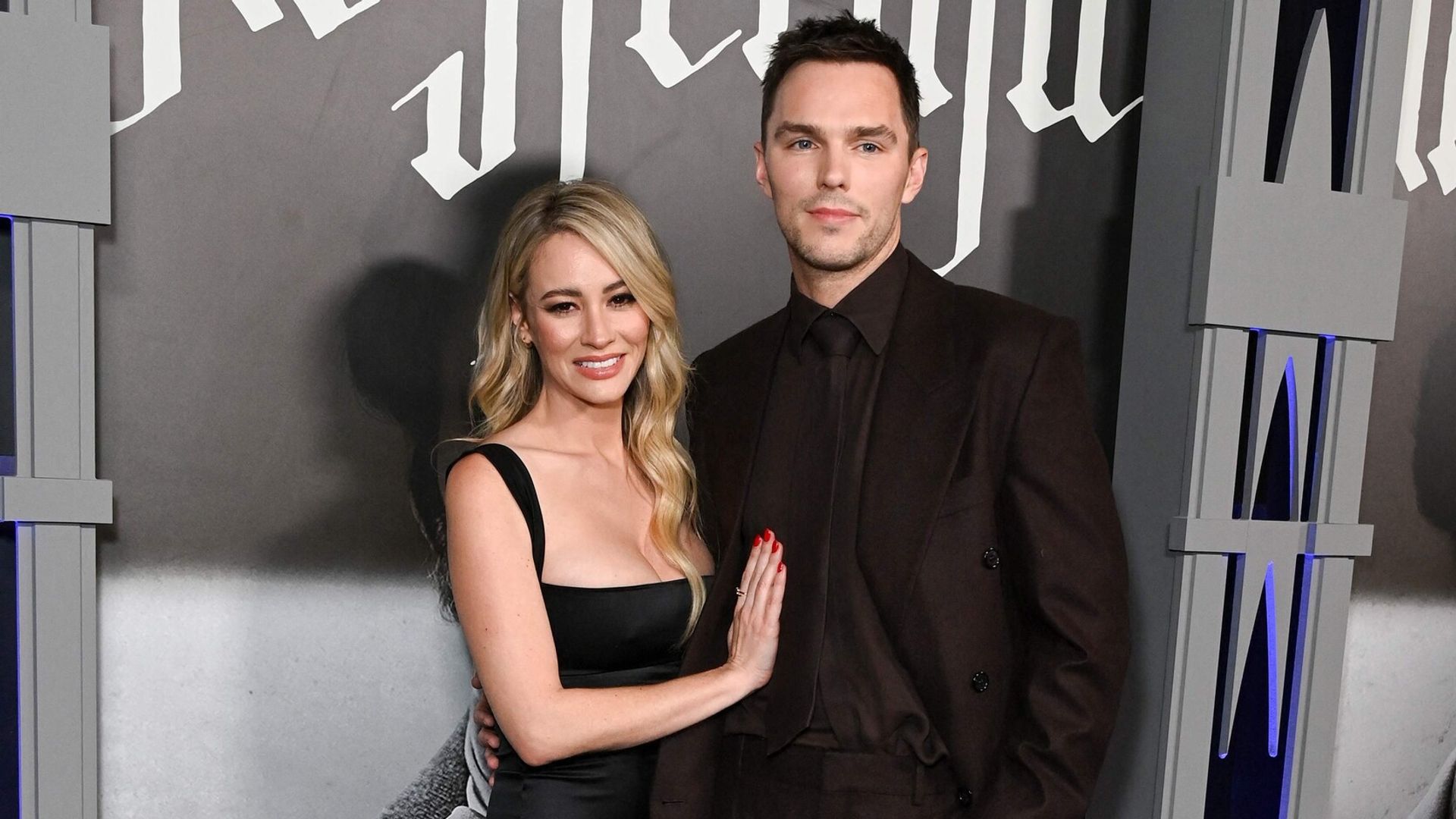 Nicholas Hoult w ciemnym garniturze i Bryana Holly w czarnej sukience pozują razem na czerwonym dywanie