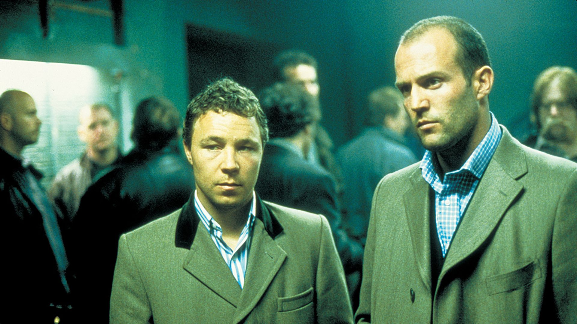 Steven Graham i Jason Statham w płaszczach stoją wśród mężczyzn