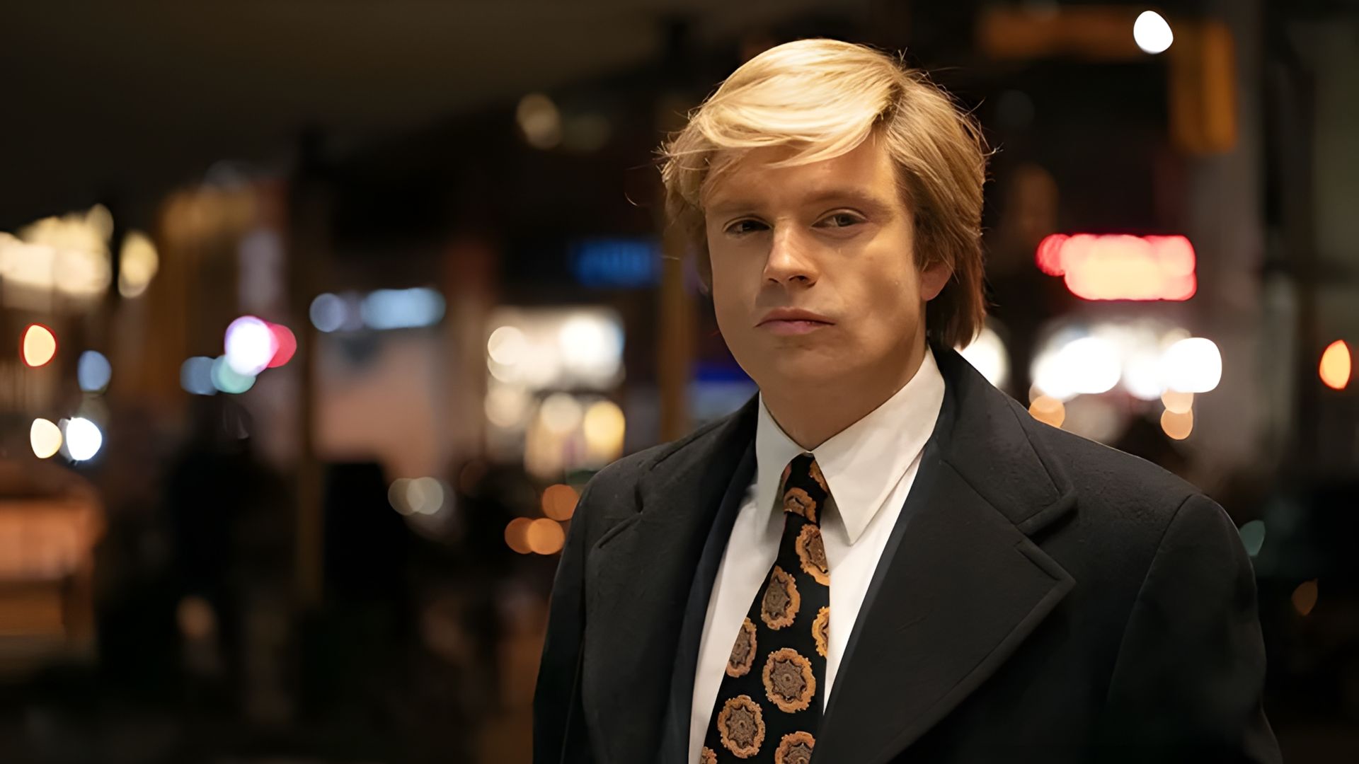 Sebastian Stan w garniturze i białej peruce patrzy w kamerę